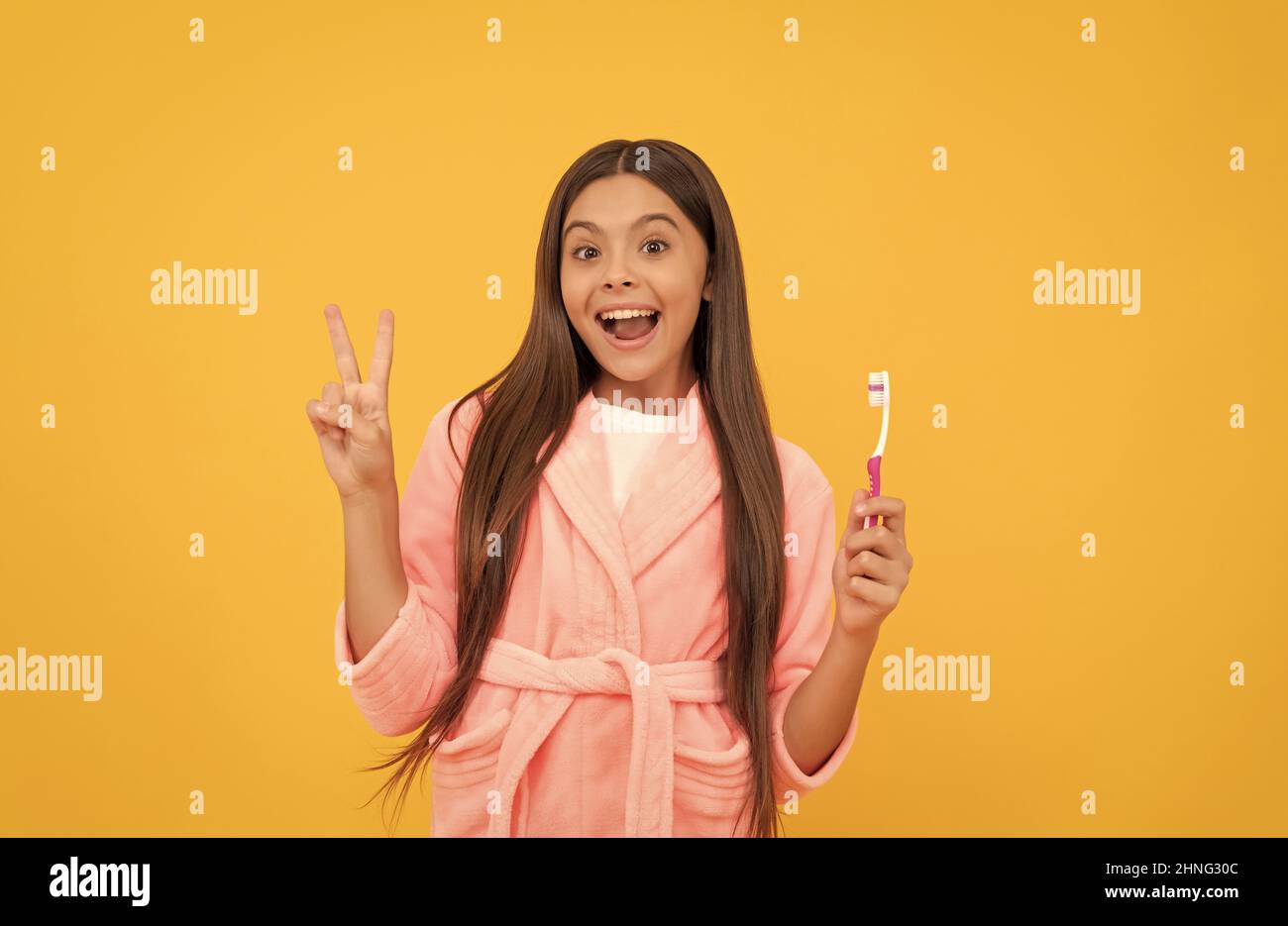 bonne surprise teen fille à la maison terry peignoir tenir brosse à dents montrer la paix geste, l'enfance Banque D'Images