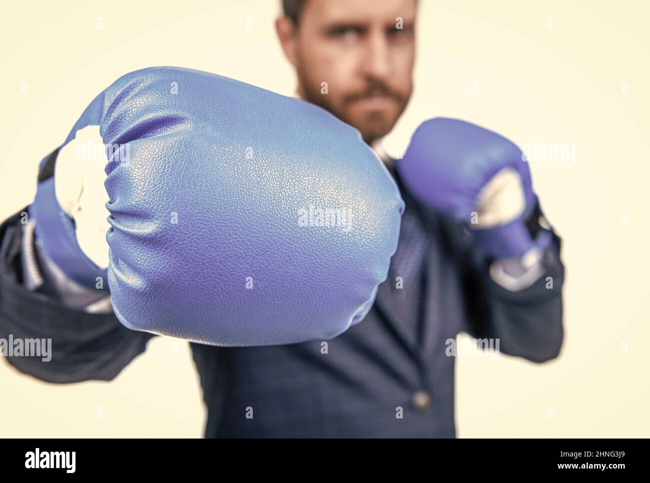 Homme d'affaires debout en position de combat avec des gants de boxe bleus, focus sélectif, poinçonnement Banque D'Images