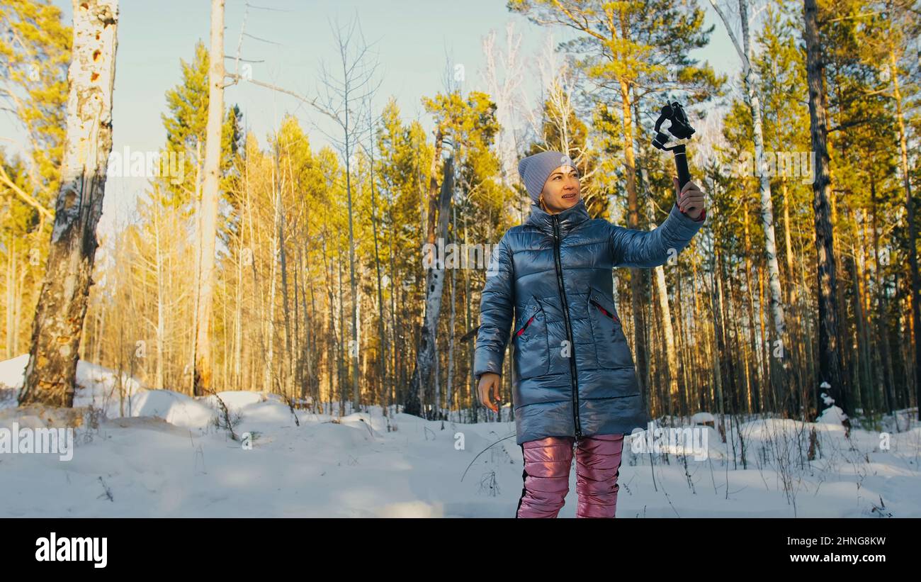 La femme vidéaste professionnelle tenant un smartphone sur le dispositif de stabilisation de nacelle 3 axes en hiver. Pro Equipment permet de réaliser des vidéos haute qualité sur téléphone. Directeur de la photographie. Ralenti Banque D'Images