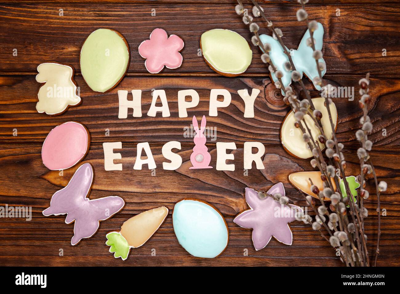 Vue de dessus de délicieux biscuits de pâques et de branches de saule sur brun foncé. Banque D'Images