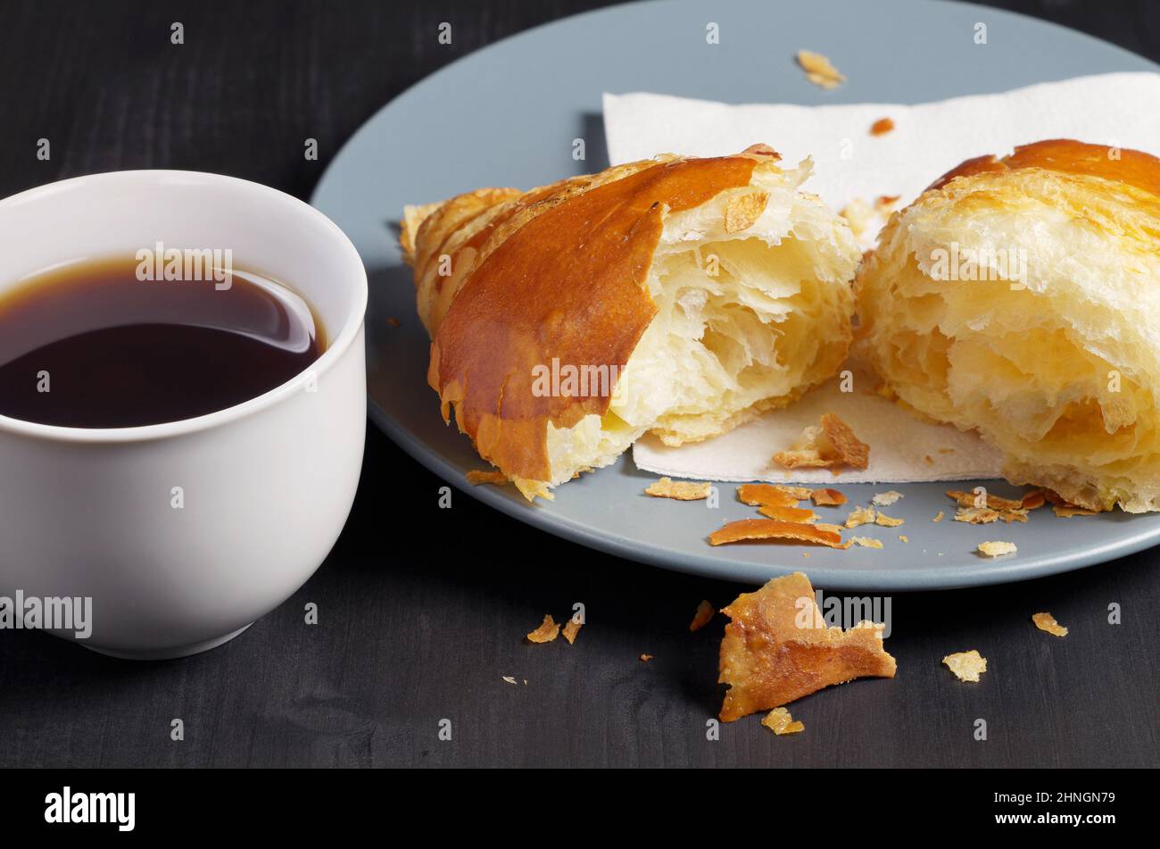 Deux demi de croissant et café sur une table en bois noir de près. Thème du petit déjeuner ou de la pause Banque D'Images