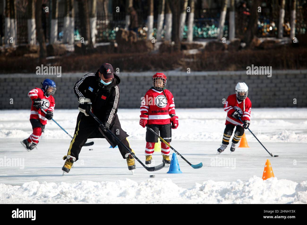 SHENYANG, CHINE - le 17 FÉVRIER 2022 - de jeunes joueurs de hockey sur glace pratiquent le hockey sur glace sous la direction d'un entraîneur dans une patinoire le 17 février 2022 i Banque D'Images