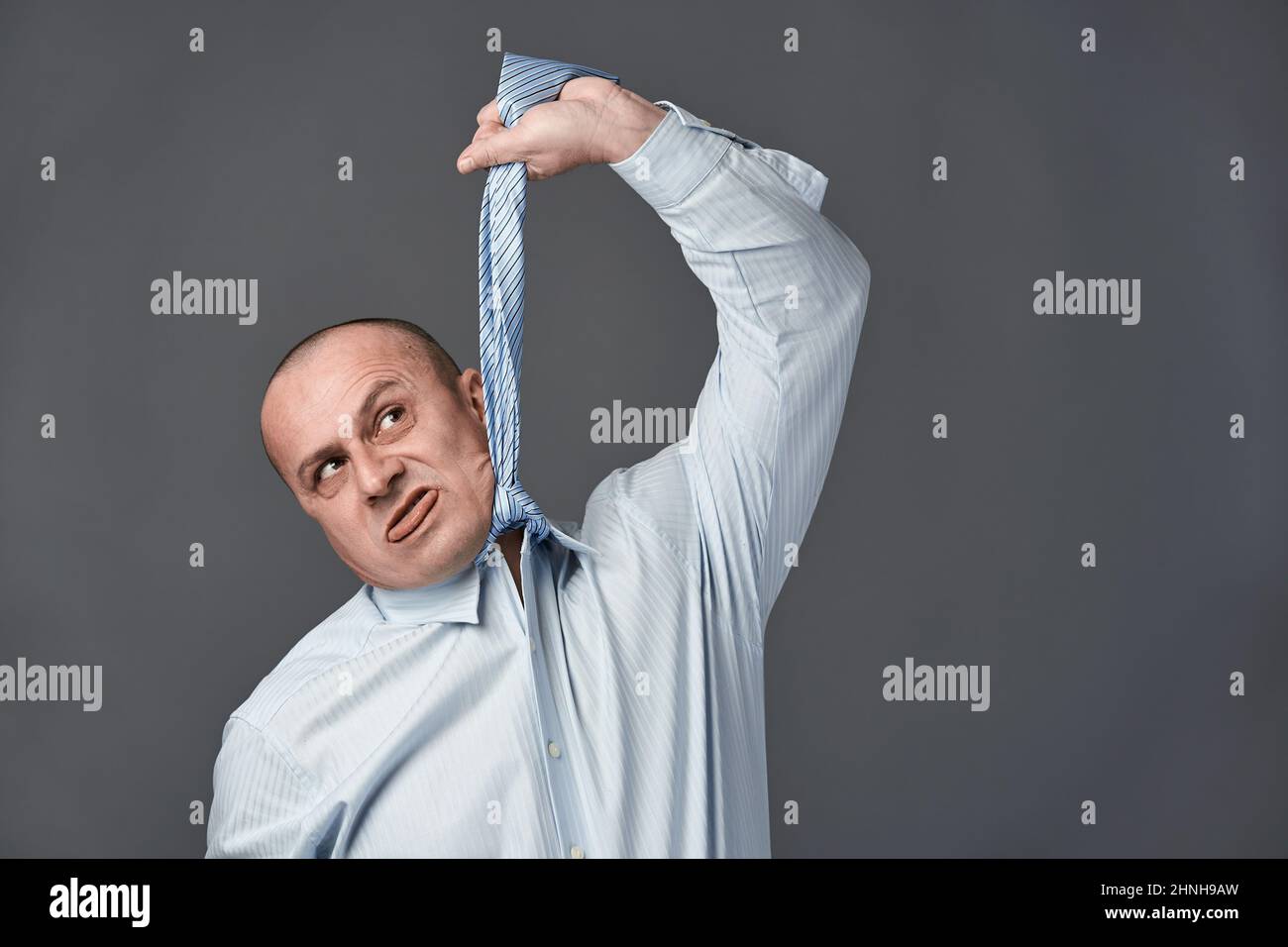 Homme d'affaires frustré imitant de se raccrocher avec son cravate Banque D'Images