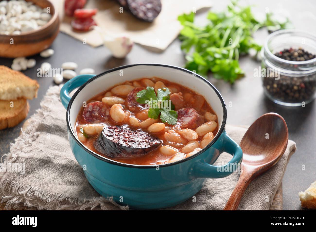 Fabada traditionnelle Asturiana avec haricot, tomates, saucisse de sang sur table brune. Gros plan. Banque D'Images