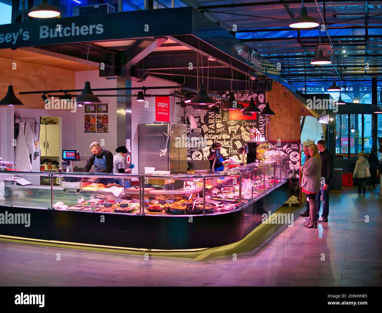 Comptoirs de boucher locaux et leurs clients dans le nouveau Market Hall de Preston, Lancashire, Royaume-Uni. Banque D'Images