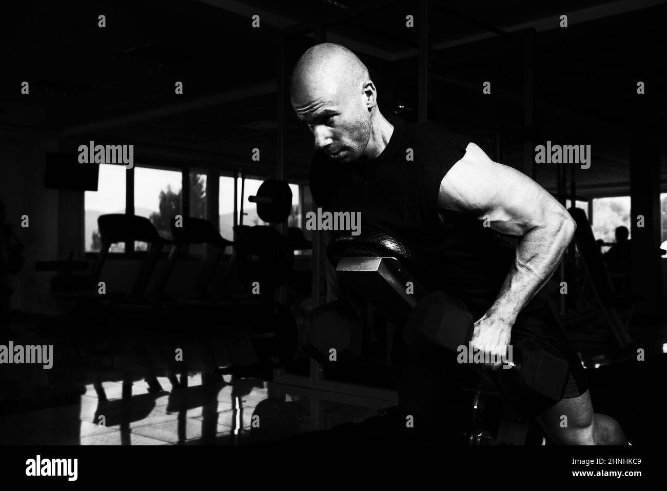 Bodybuilder sérieux faisant poids lourd de l'exercice ou à l'arrière du trapèze avec haltères Banque D'Images