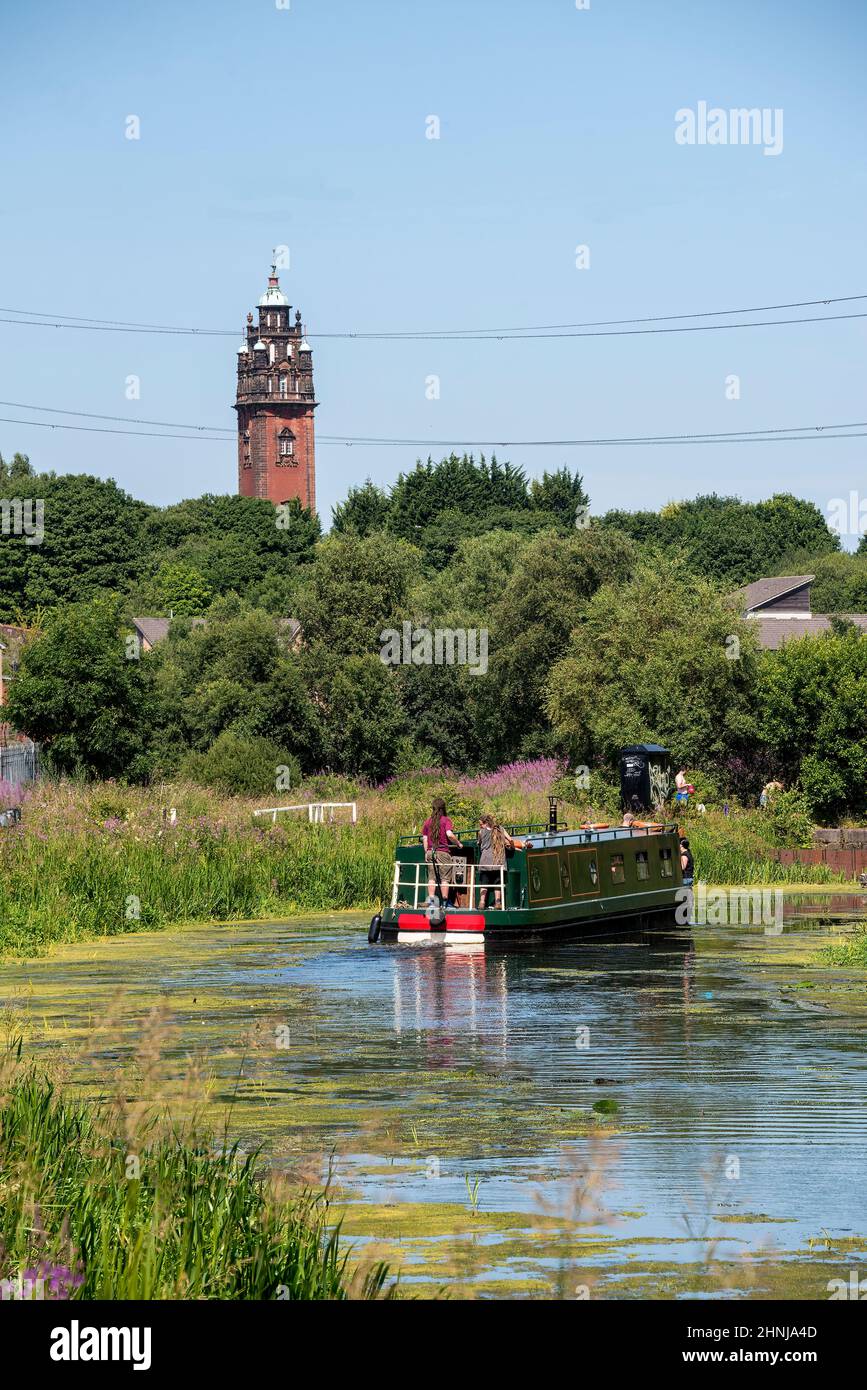 Bateau naviguant le long du canal Forth & Clyde avec vue sur la tour historique de l'ancien hôpital Ruchill abandonné. Banque D'Images