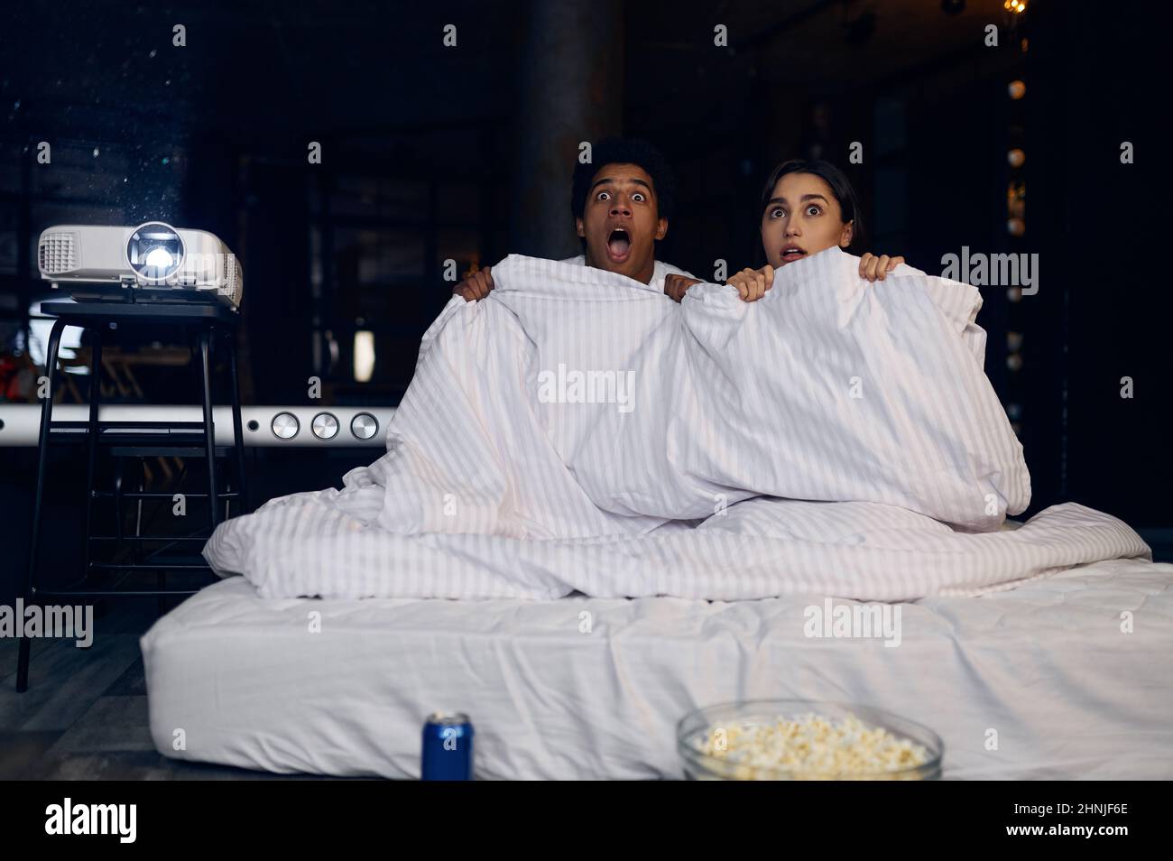 Couple drôle regardant un film d'horreur sous une couverture Banque D'Images