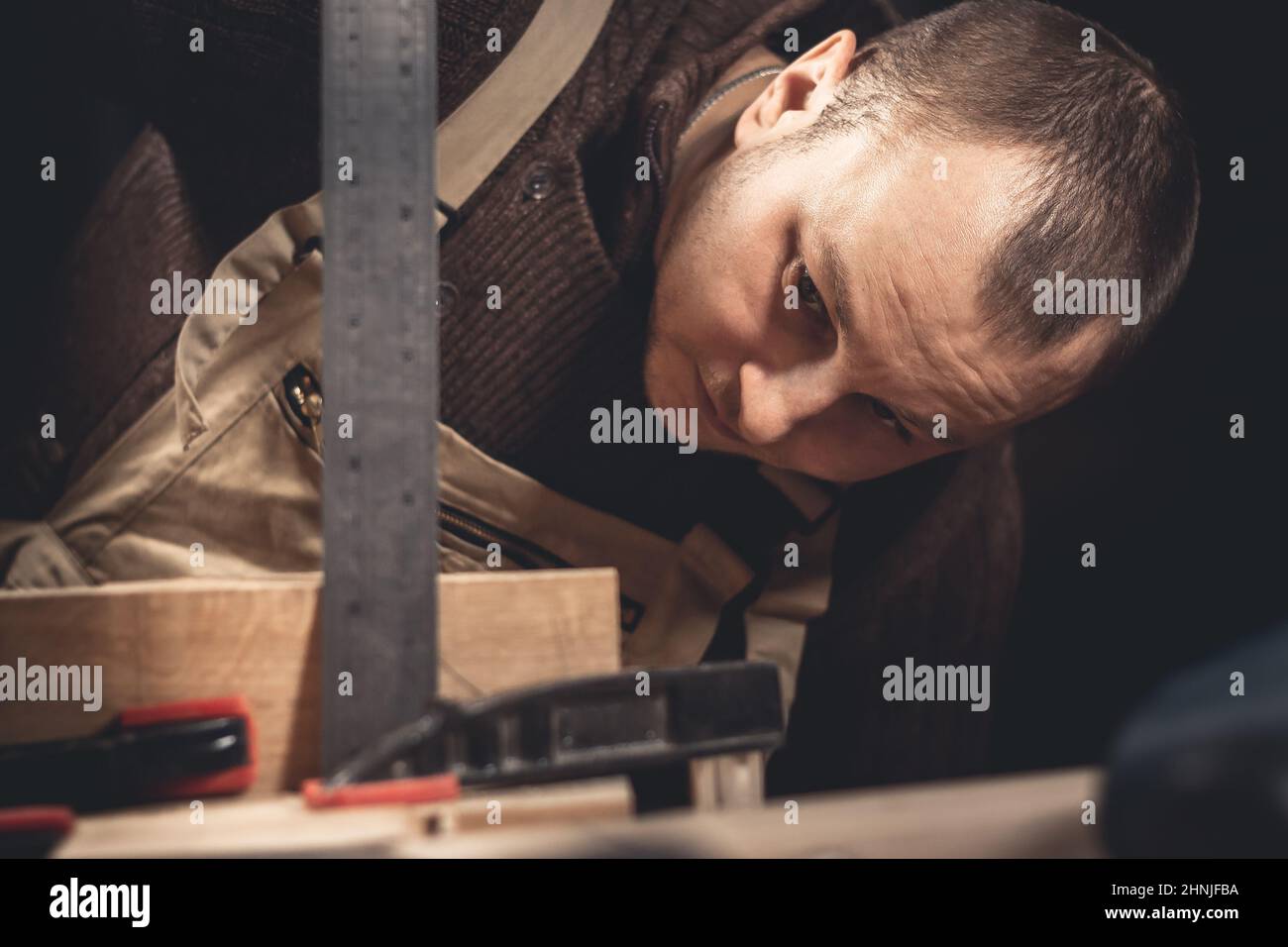Un homme fabrique des produits en bois à l'aide d'outils spéciaux. Portrait d'un jeune menuisier au travail. Emploi dans l'industrie du bois Banque D'Images