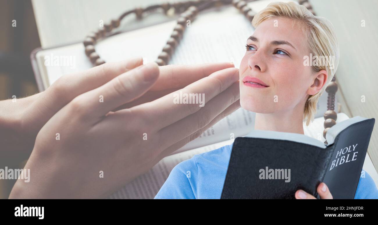 Une jeune femme caucasienne tient la bible tout en regardant loin avec les mains jointes sur le livre en arrière-plan Banque D'Images