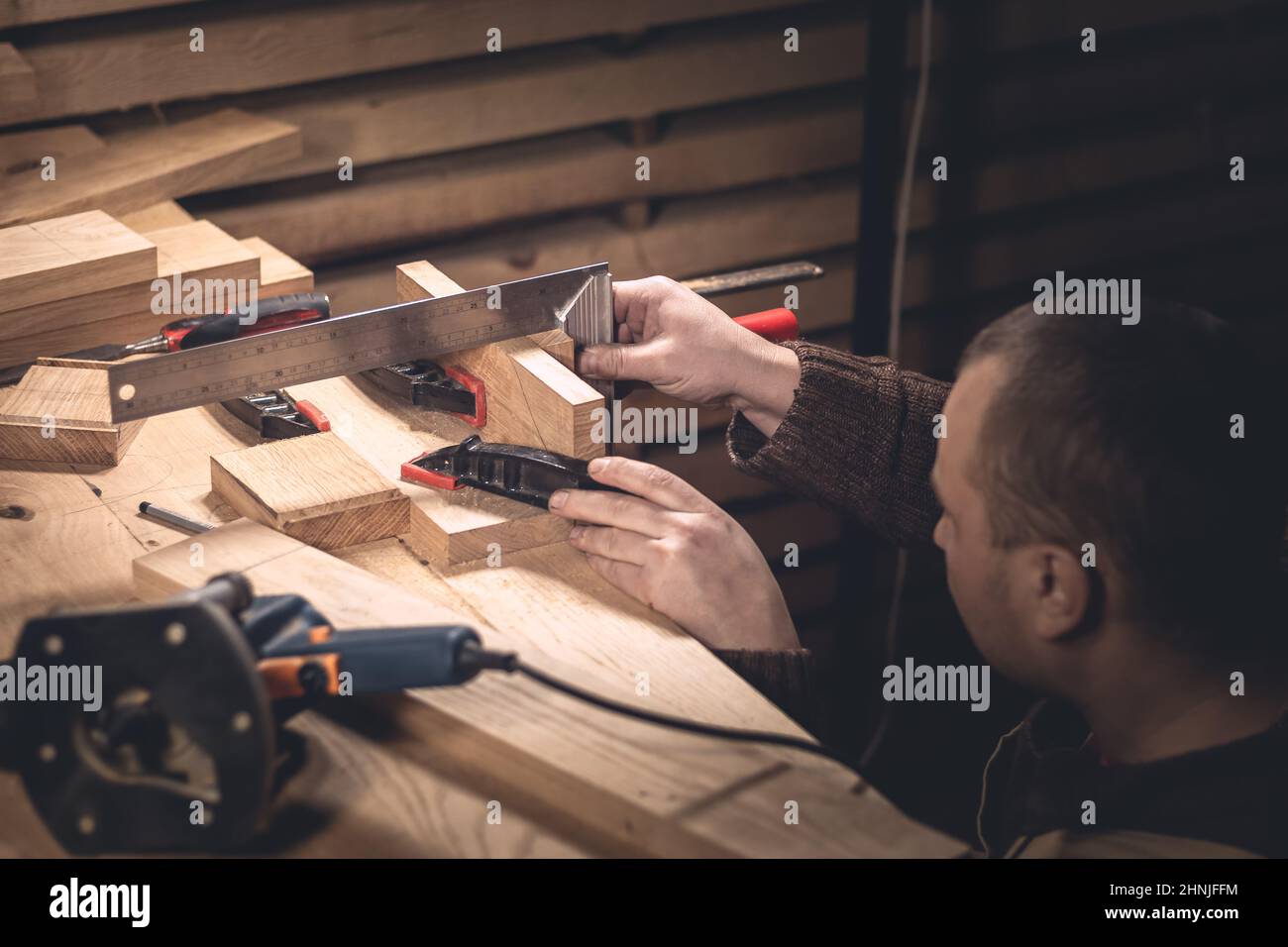 Un homme fabrique des produits en bois à l'aide d'outils spéciaux. Portrait d'un jeune menuisier au travail. Emploi dans l'industrie du bois Banque D'Images