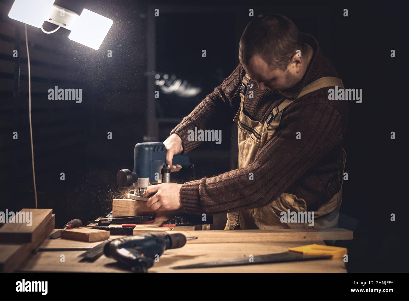 Un homme fabrique des produits en bois à l'aide d'outils spéciaux. Portrait d'un jeune menuisier au travail. Emploi dans l'industrie du bois Banque D'Images
