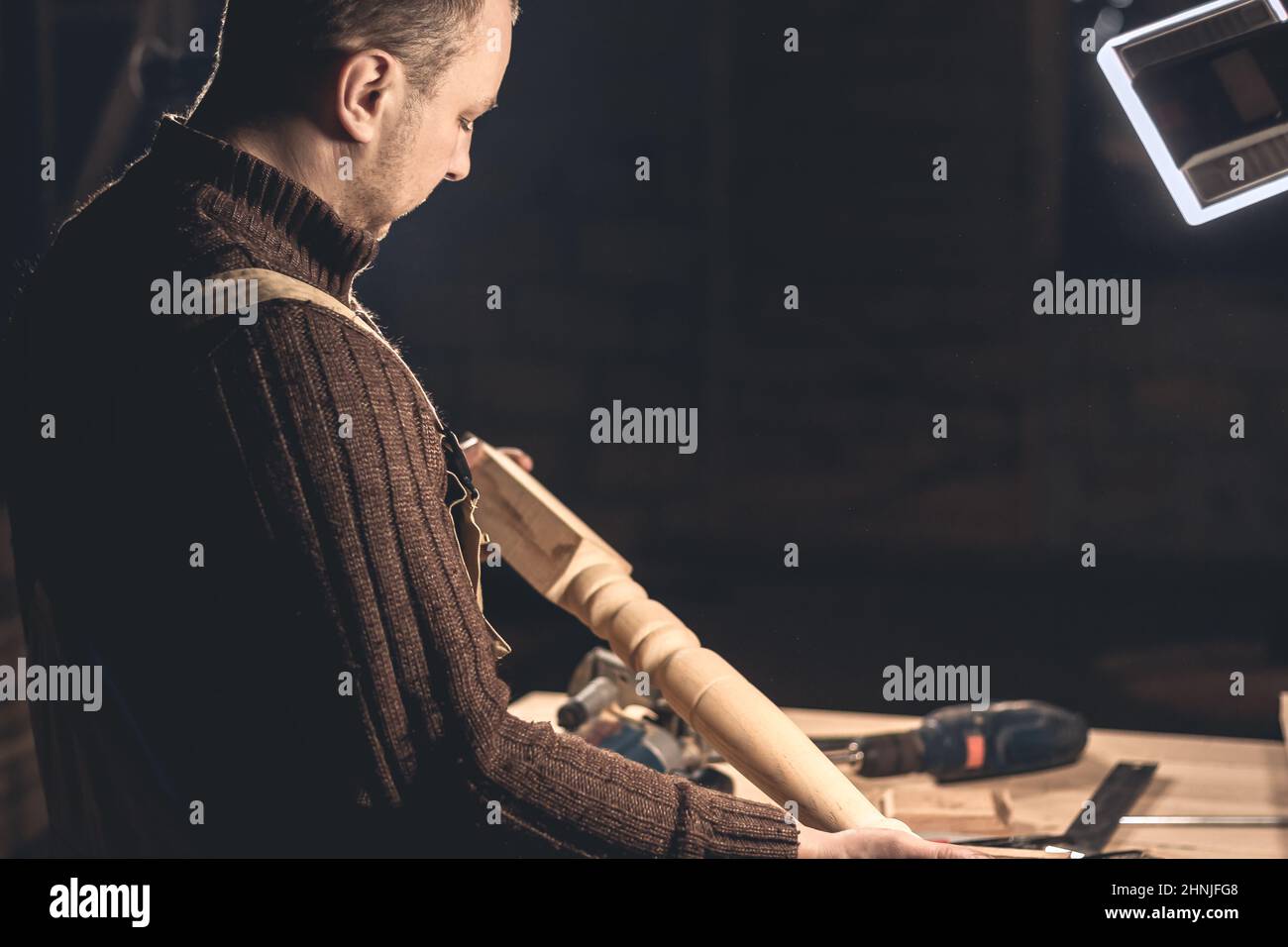 Un homme fabrique des produits en bois à l'aide d'outils spéciaux. Portrait d'un jeune menuisier au travail. Emploi dans l'industrie du bois Banque D'Images