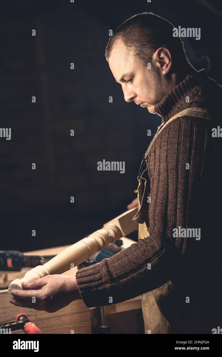 Un homme fabrique des produits en bois à l'aide d'outils spéciaux. Portrait d'un jeune menuisier au travail. Emploi dans l'industrie du bois Banque D'Images