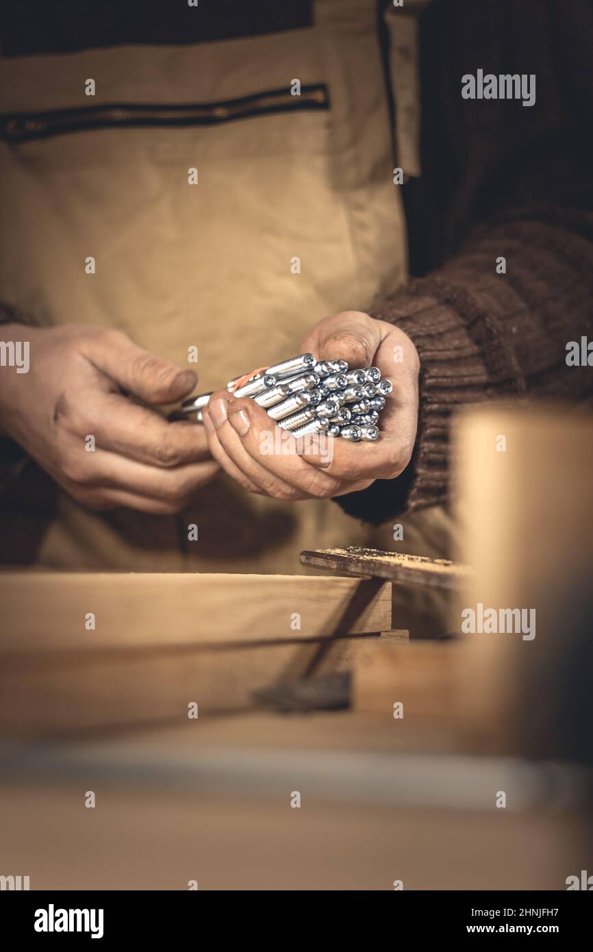 Un homme fabrique des produits en bois à l'aide d'outils spéciaux. Portrait d'un jeune menuisier au travail. Emploi dans l'industrie du bois Banque D'Images