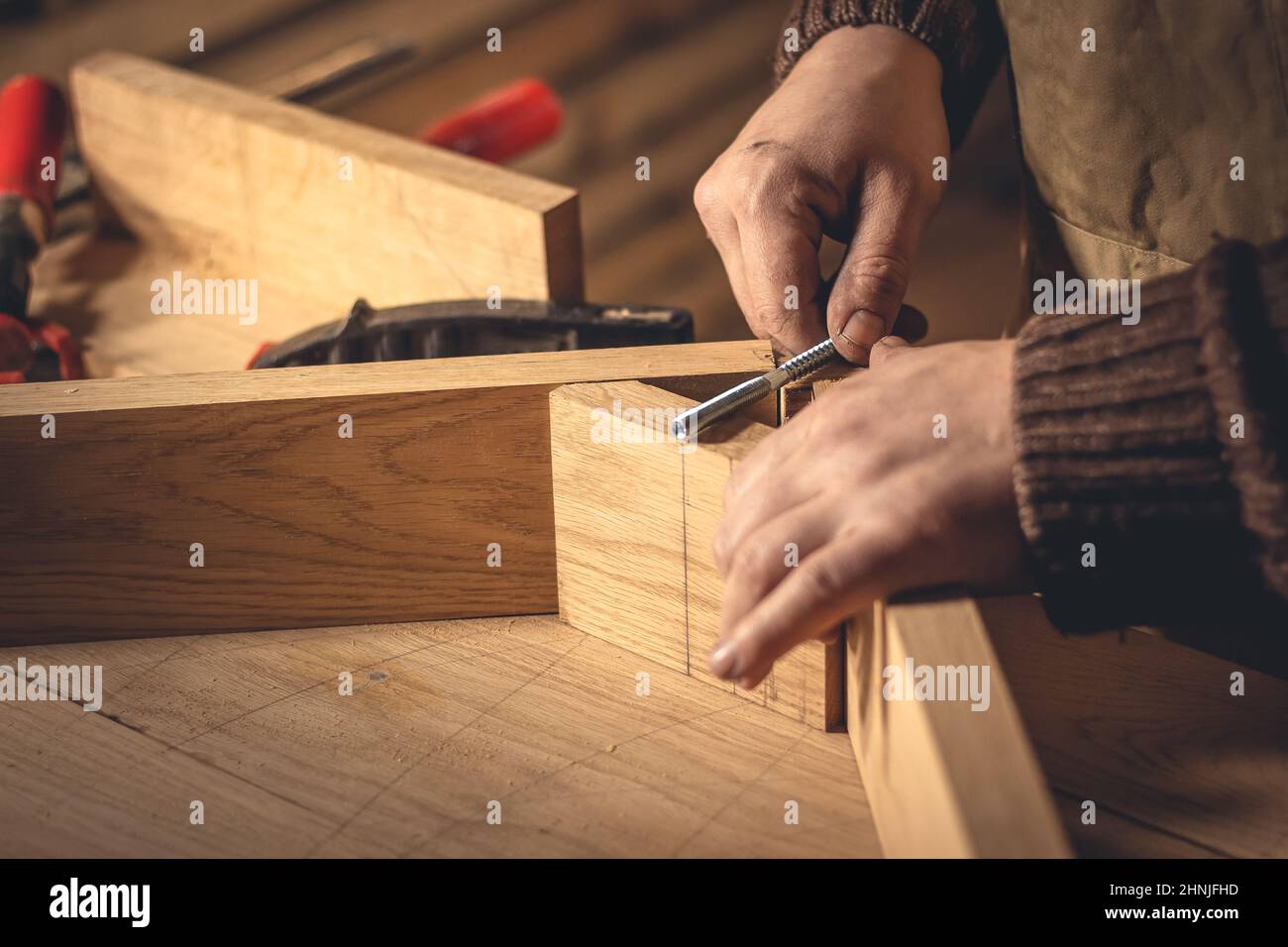 Un homme fabrique des produits en bois à l'aide d'outils spéciaux. Portrait d'un jeune menuisier au travail. Emploi dans l'industrie du bois Banque D'Images