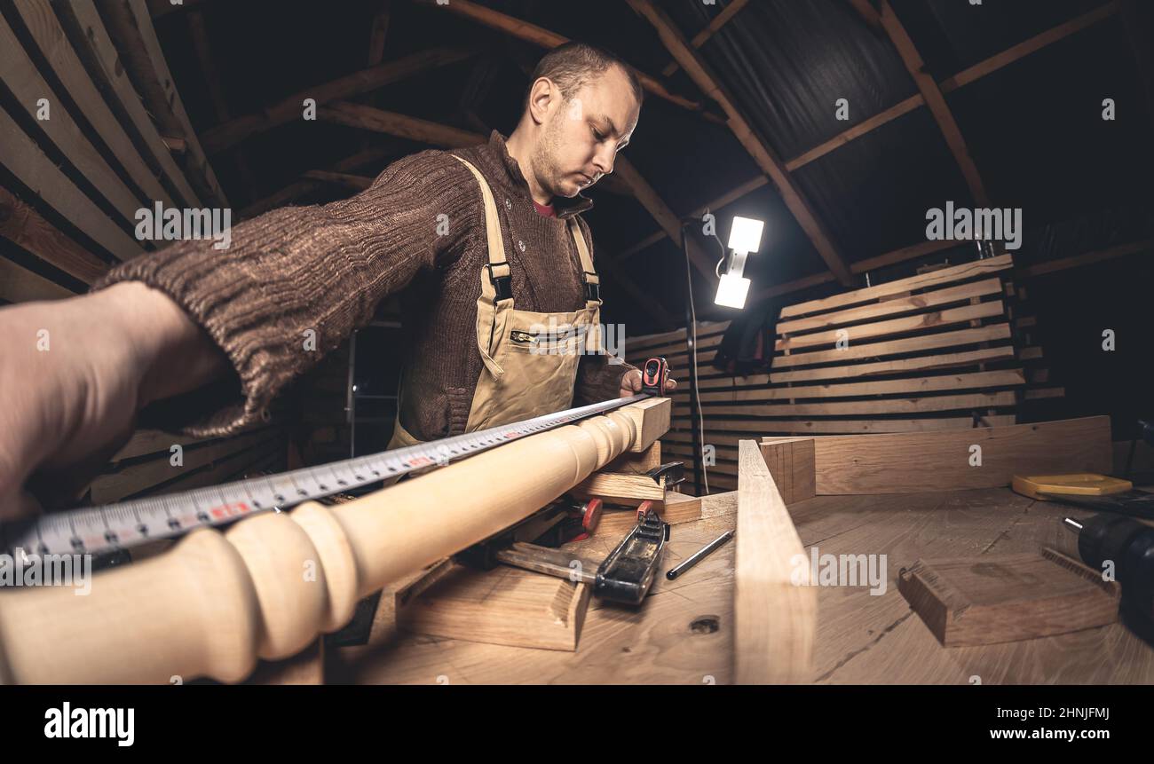 Un homme fabrique des produits en bois à l'aide d'outils spéciaux. Portrait d'un jeune menuisier au travail. Emploi dans l'industrie du bois Banque D'Images