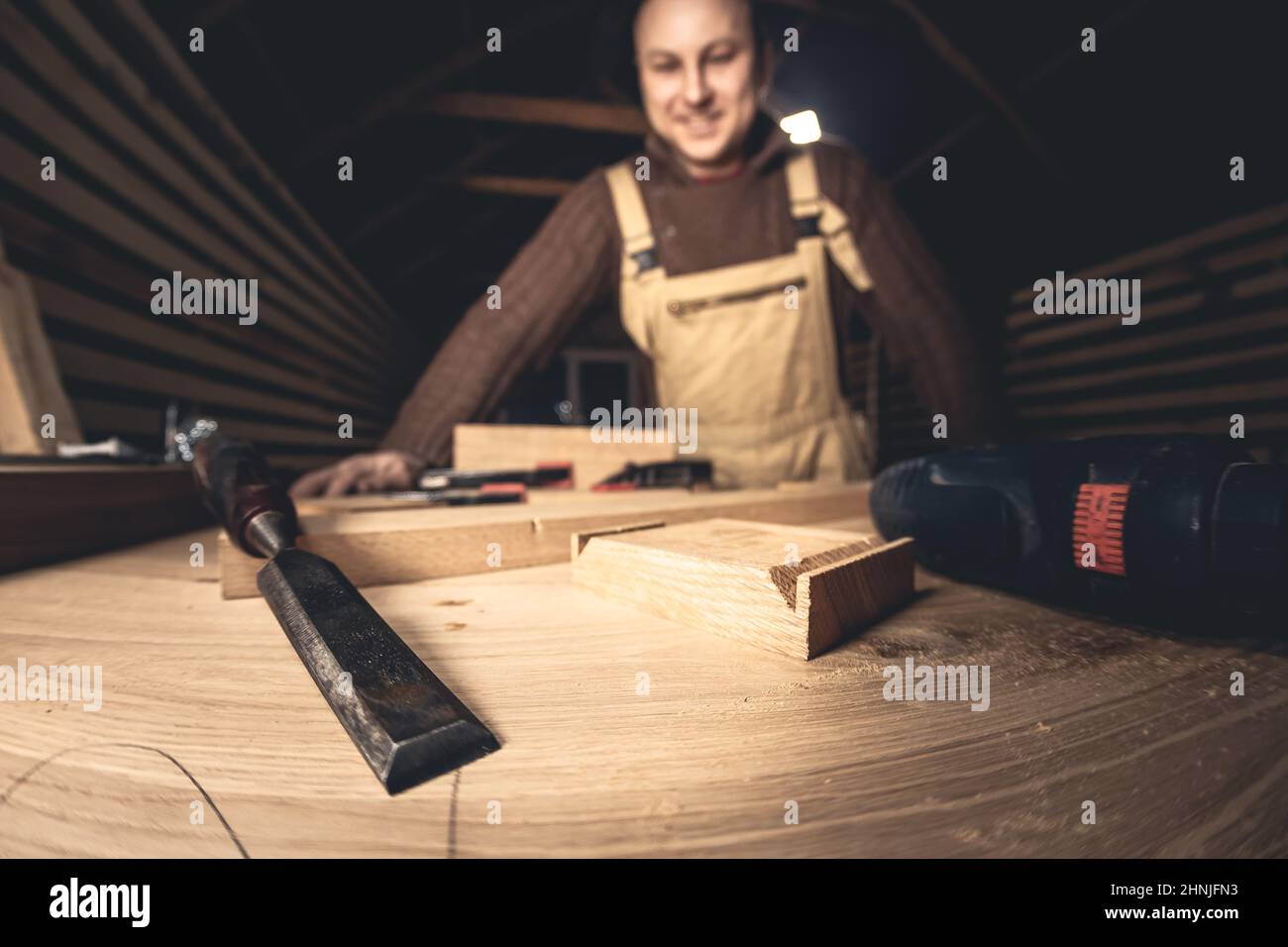 Un homme fabrique des produits en bois à l'aide d'outils spéciaux. Portrait d'un jeune menuisier au travail. Emploi dans l'industrie du bois Banque D'Images