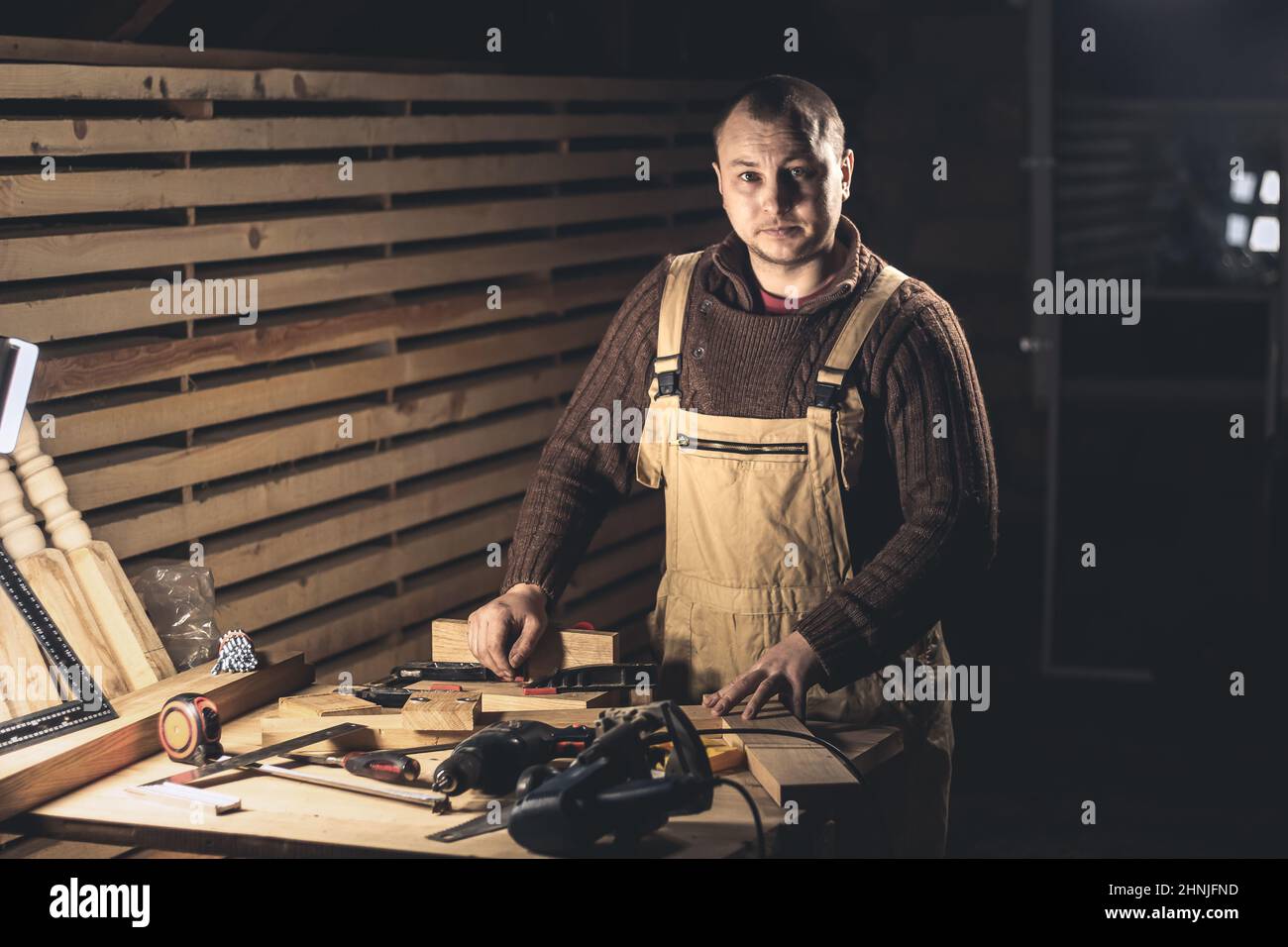 Un homme fabrique des produits en bois à l'aide d'outils spéciaux. Portrait d'un jeune menuisier au travail. Emploi dans l'industrie du bois Banque D'Images
