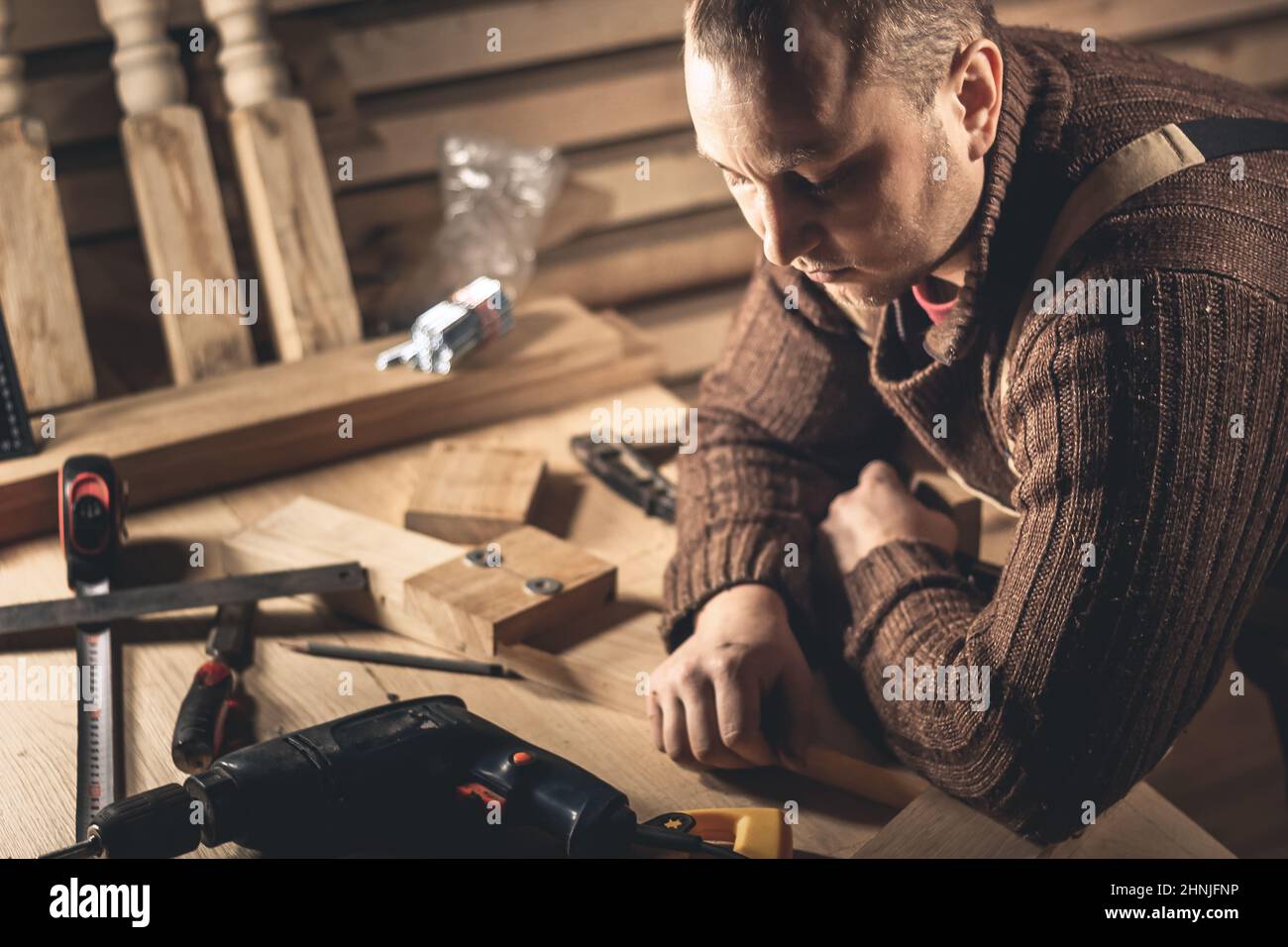 Un homme fabrique des produits en bois à l'aide d'outils spéciaux. Portrait d'un jeune menuisier au travail. Emploi dans l'industrie du bois Banque D'Images