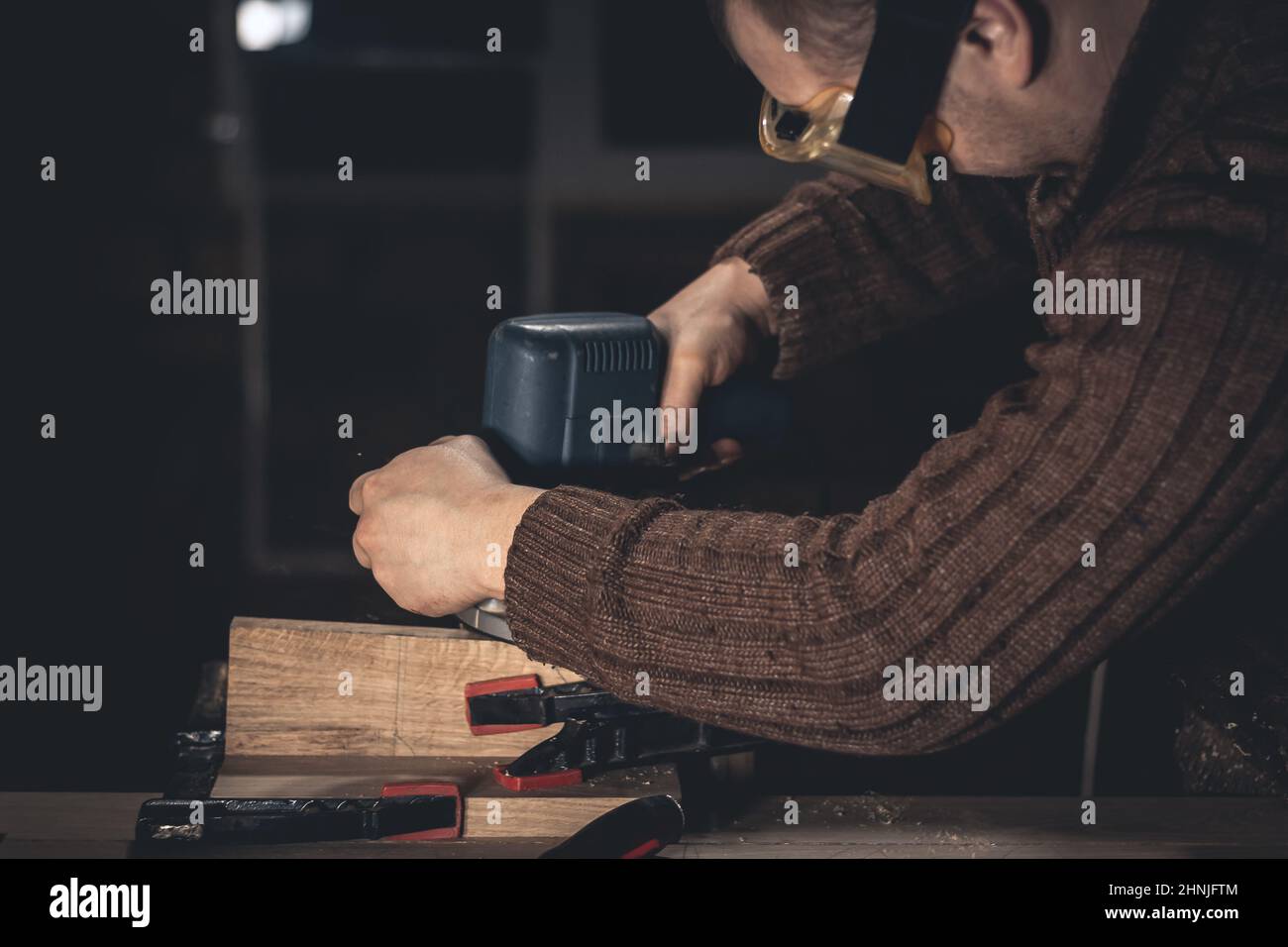 Un homme fabrique des produits en bois à l'aide d'outils spéciaux. Portrait d'un jeune menuisier au travail. Emploi dans l'industrie du bois Banque D'Images