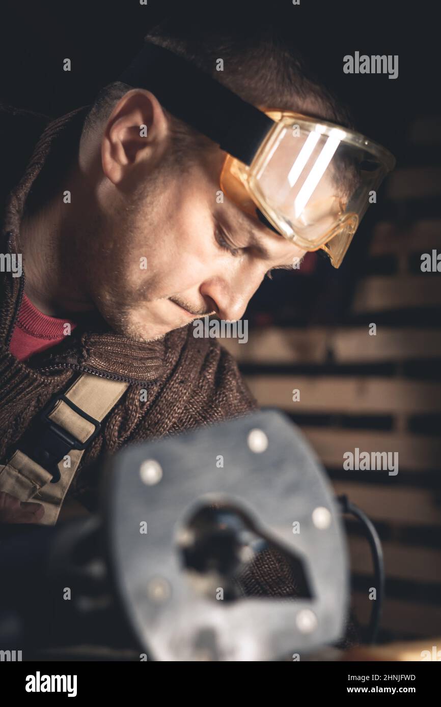 Un homme fabrique des produits en bois à l'aide d'outils spéciaux. Portrait d'un jeune menuisier au travail. Emploi dans l'industrie du bois Banque D'Images