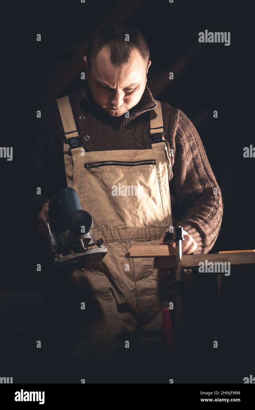 Un homme fabrique des produits en bois à l'aide d'outils spéciaux. Portrait d'un jeune menuisier au travail. Emploi dans l'industrie du bois Banque D'Images