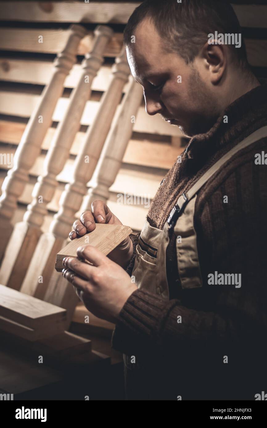Un homme fabrique des produits en bois à l'aide d'outils spéciaux. Portrait d'un jeune menuisier au travail. Emploi dans l'industrie du bois Banque D'Images