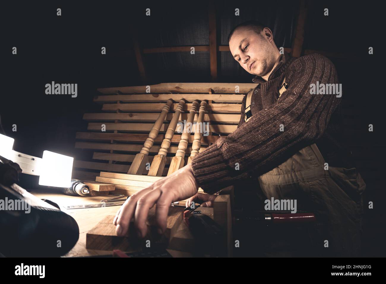 Un homme fabrique des produits en bois à l'aide d'outils spéciaux. Portrait d'un jeune menuisier au travail. Emploi dans l'industrie du bois Banque D'Images