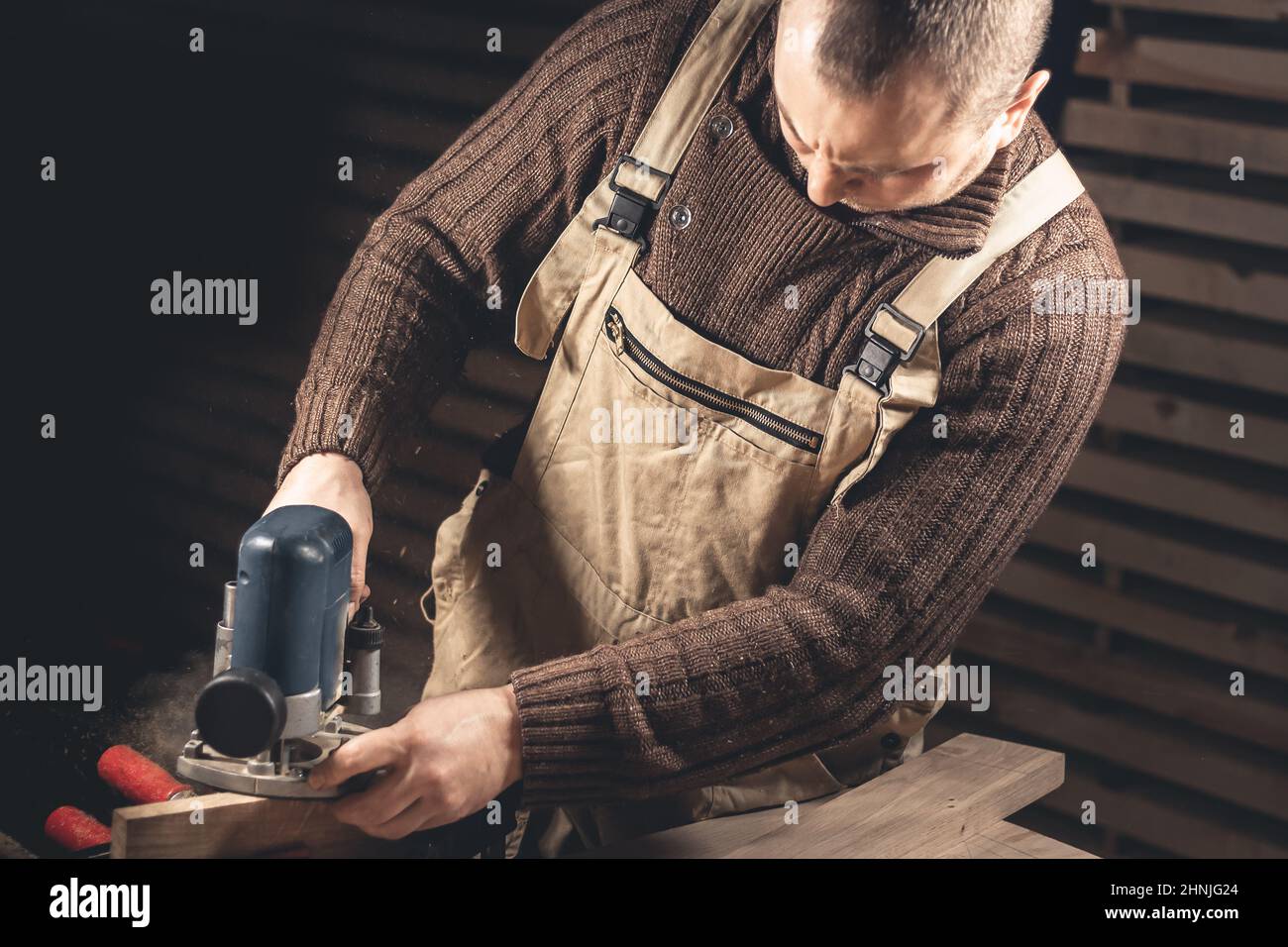 Un homme fabrique des produits en bois à l'aide d'outils spéciaux. Portrait d'un jeune menuisier au travail. Emploi dans l'industrie du bois Banque D'Images