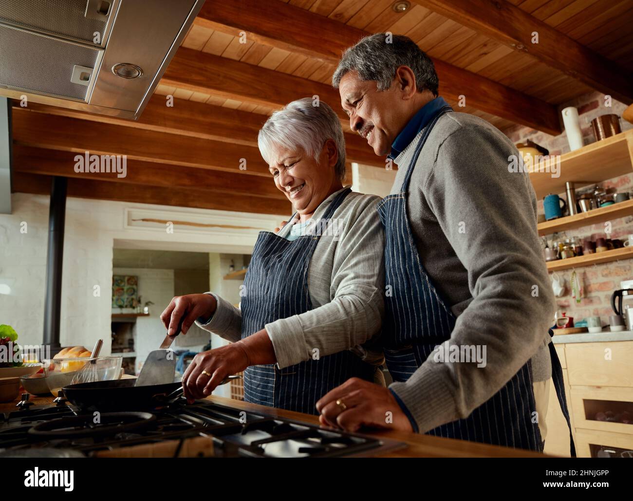 Un couple multiethnique âgé est heureux de préparer son petit déjeuner dans sa cuisine moderne. Banque D'Images