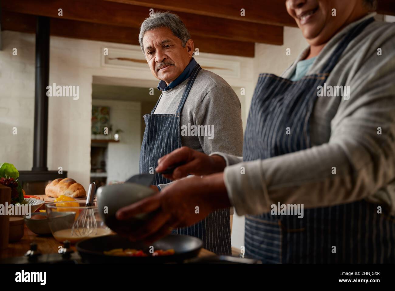 Un couple multiethnique âgé se fait un plaisir de préparer un petit déjeuner sain dans une cuisine moderne. Un mode de vie sain, à la retraite. Banque D'Images