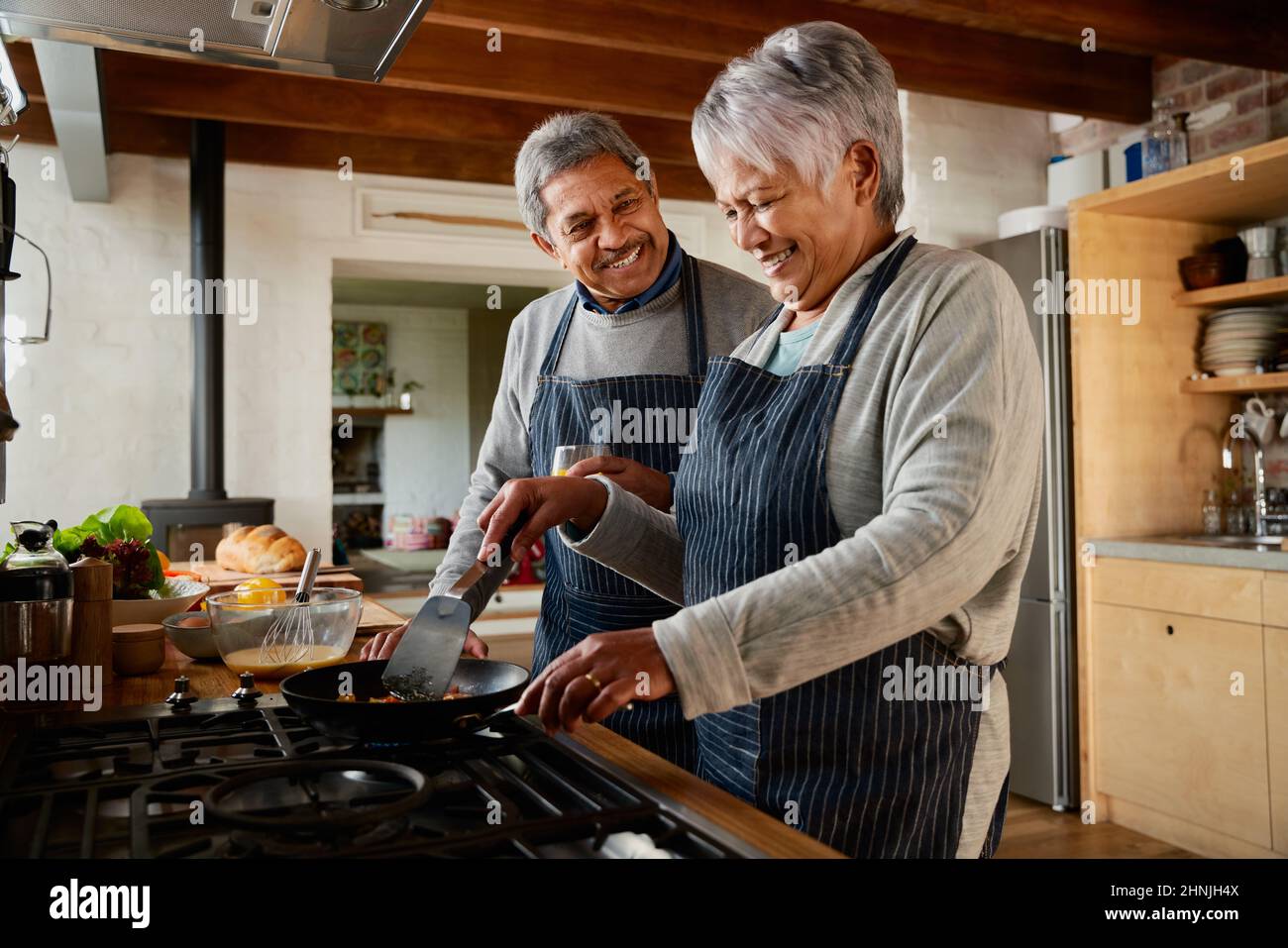 Un couple multiethnique âgé riant ensemble dans la cuisine. Heureusement à la retraite et à la cuisine du petit déjeuner les uns avec les autres. Banque D'Images