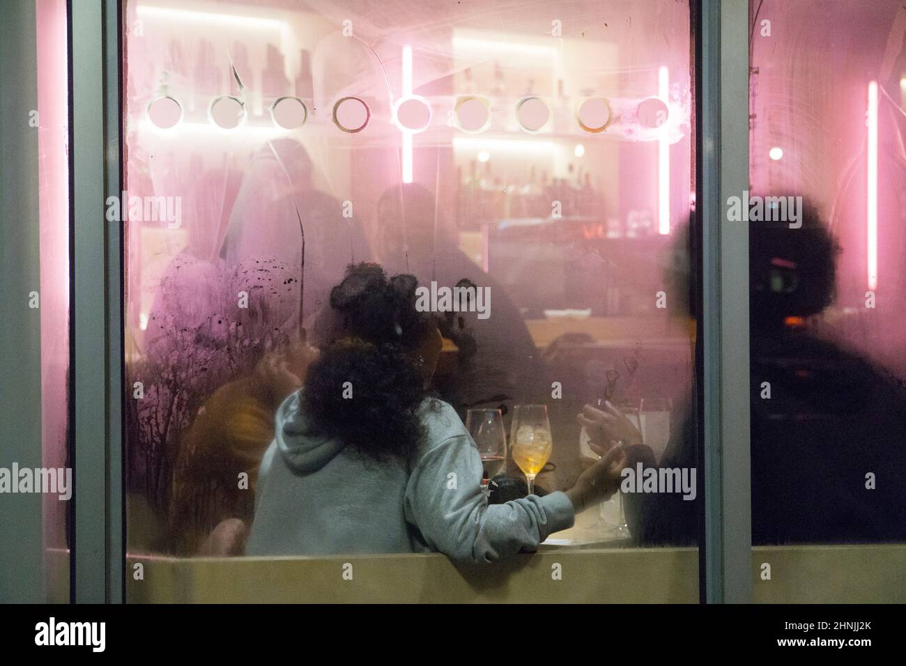 Londres, Royaume-Uni, 16 février 2022 : au bar du cinéma Curzon Soho, un groupe de personnes s'assoient à une table avec des boissons dans des verres à vin, baignés de lumière rose à partir de néons. Puisque l'Angleterre a réduit les restrictions de la cavique aux niveaux du Plan A et les supprimera entièrement au début de la semaine prochaine, les secteurs de l'hôtellerie et du divertissement espèrent un rebond financier après les pertes de la pandémie. Anna Watson/Alay Live News Banque D'Images