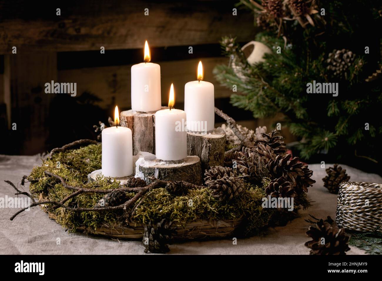 Décoration intérieure de style rustique de mode de Noël. Couronne de mousse naturelle de bricolage et bougies de l'Avent sur la table. Palette en bois comme arrière-plan. Mode ECO ven Banque D'Images
