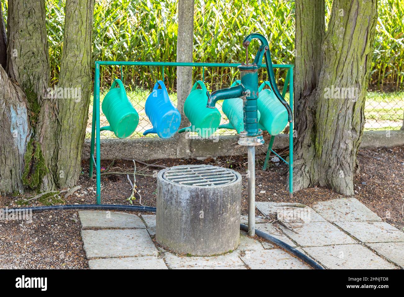 Arrosoir suspendu à côté d'une vieille pompe à eau au cimetière municipal. Quelques équipements de jardinage au cimetière pour prendre soin de la verdure grave Banque D'Images