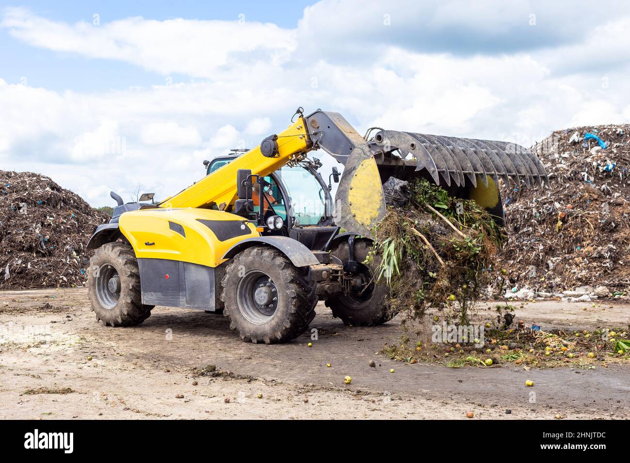 Bulldozer déplacement des déchets organiques à l'usine de recyclage du compost. Terrassement travaillant sur un tas de compost dans une installation industrielle Banque D'Images