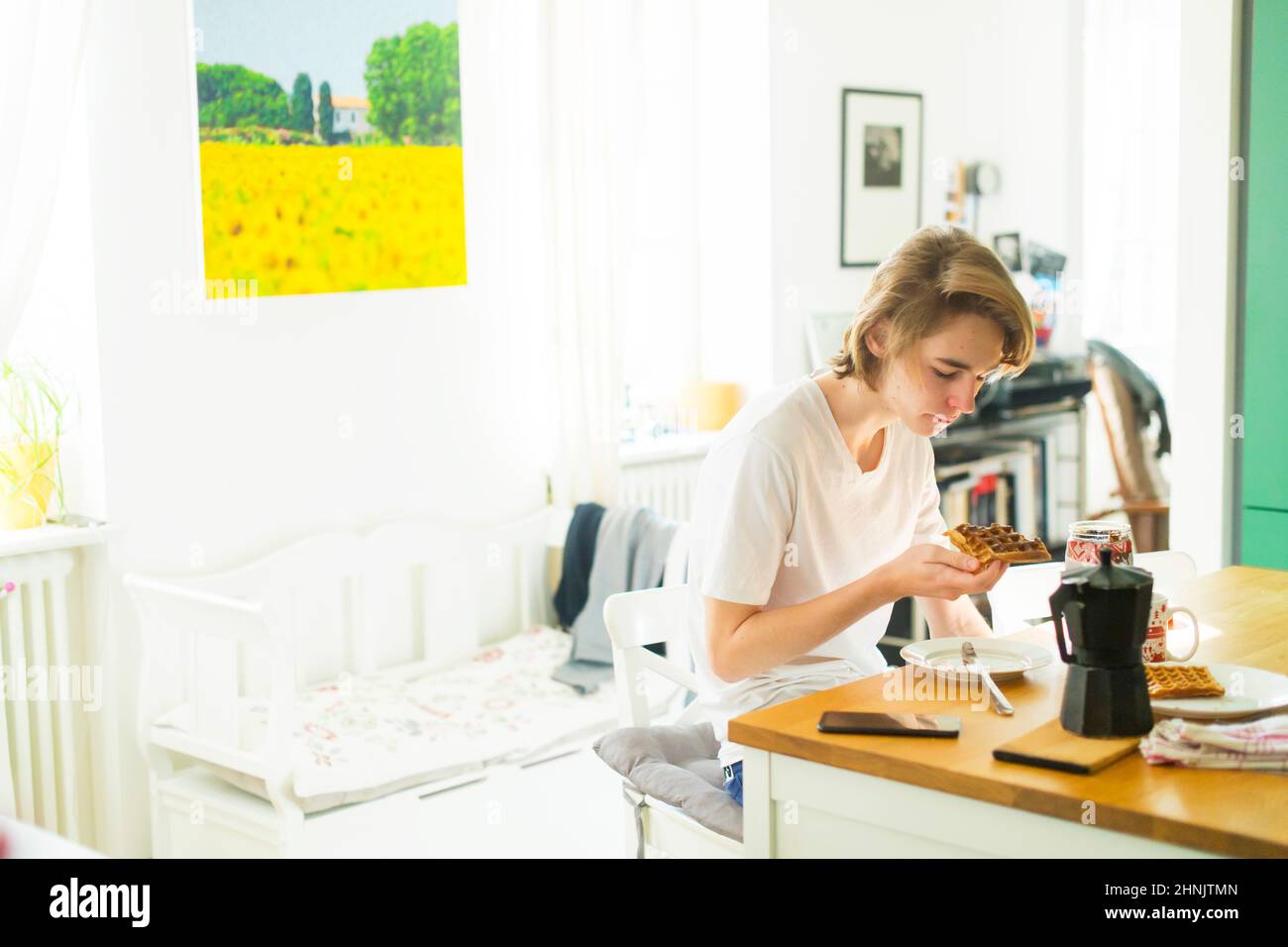 adolescent prenant le petit déjeuner à la journée ensoleillée dans la cuisine maison Banque D'Images