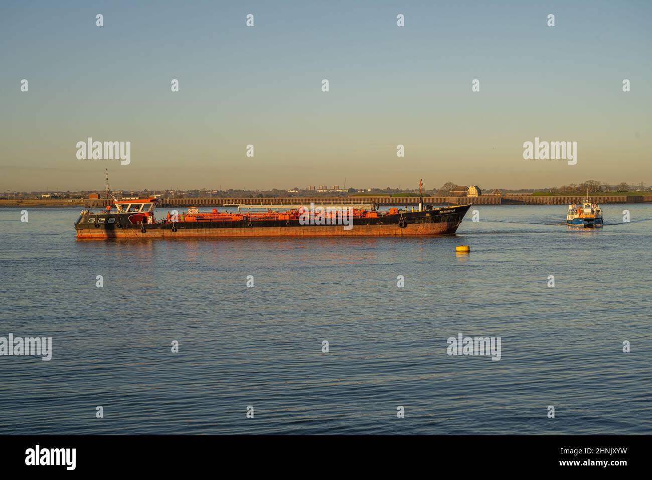 Distributeur d'un bateau-citerne à carburant au large de la jetée de la ville à Gravesend avec le ferry de Tilbury derrière Banque D'Images