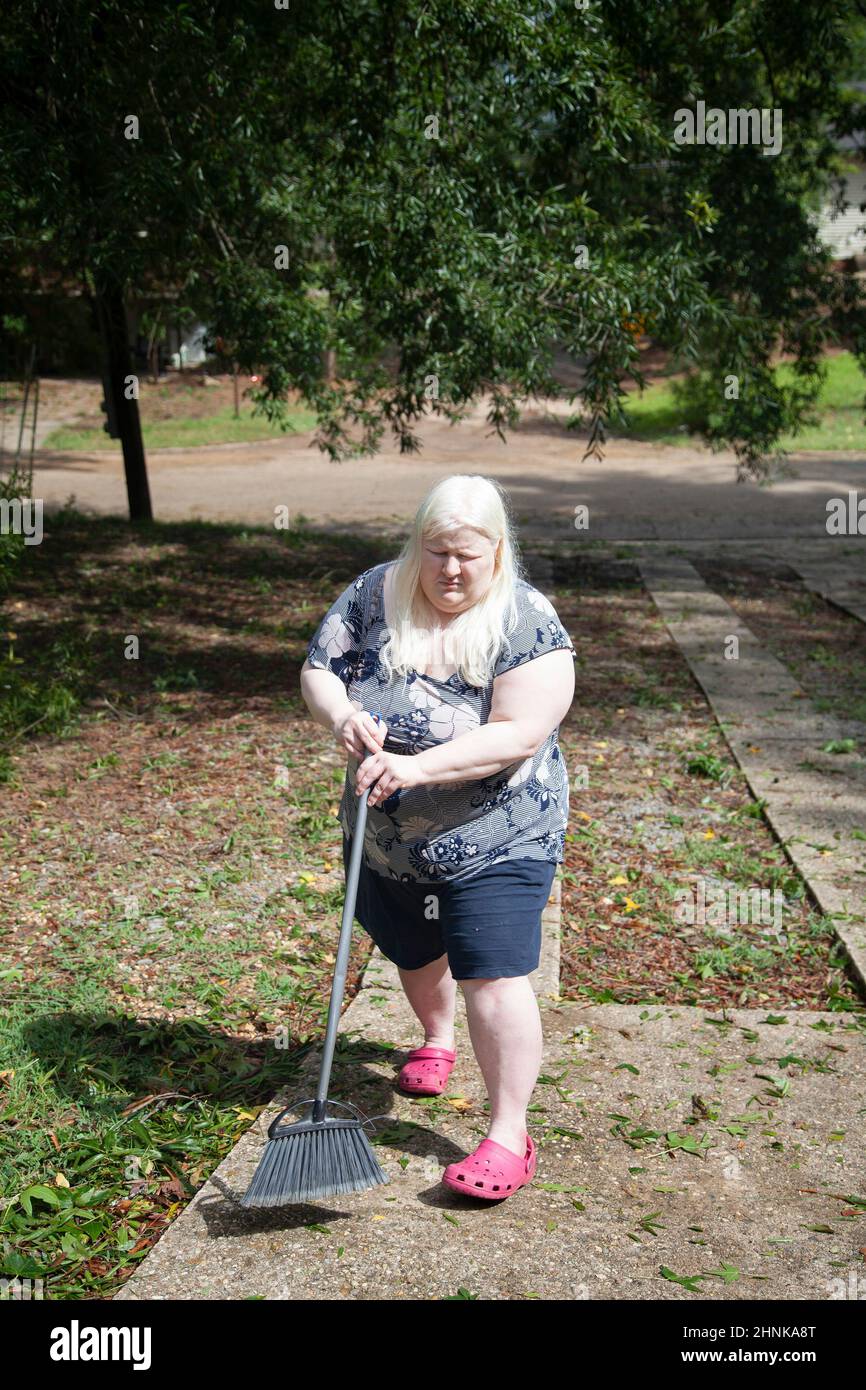 Femme nettoyant un yard Banque D'Images