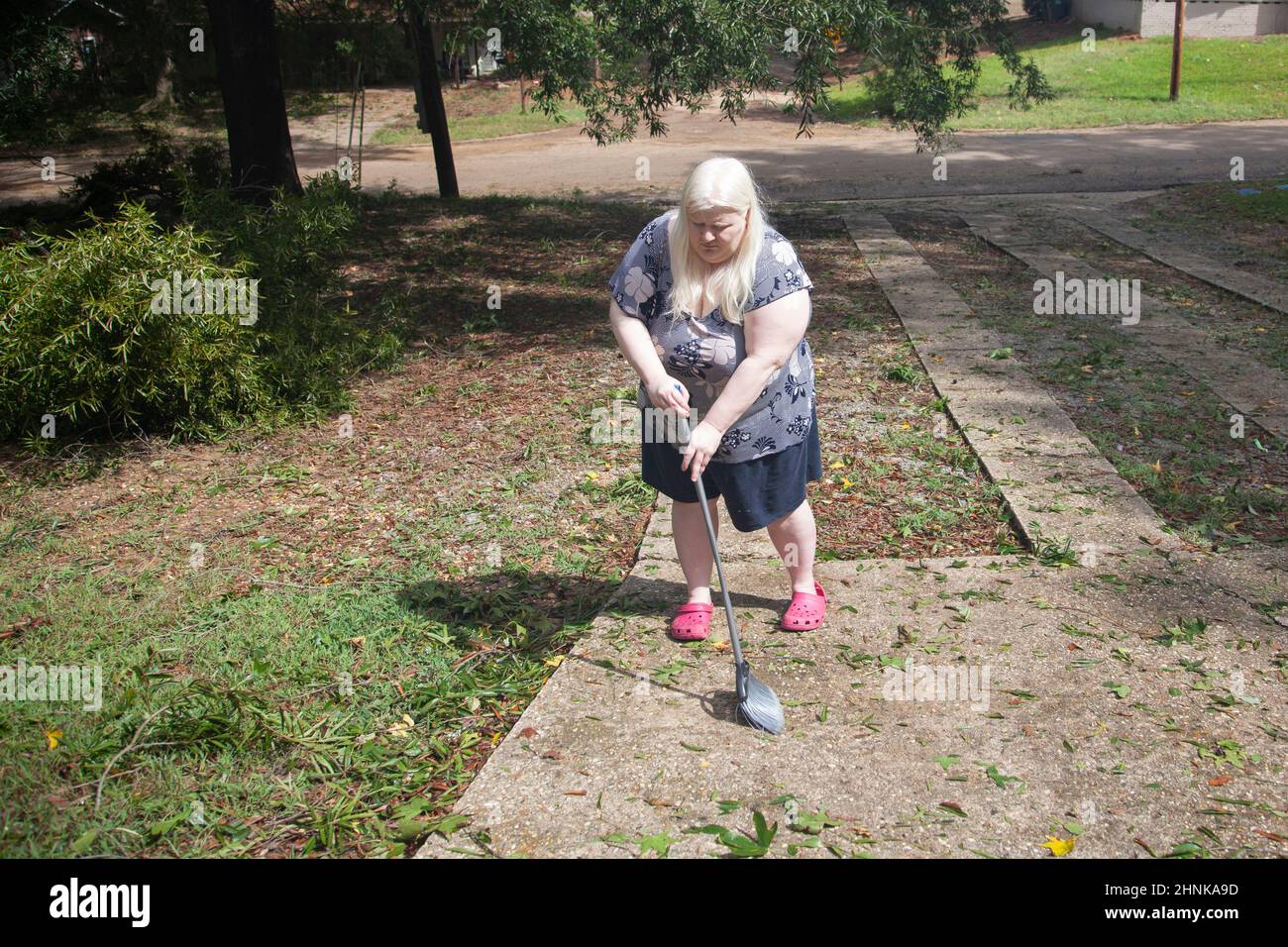 Femme nettoyant un yard Banque D'Images