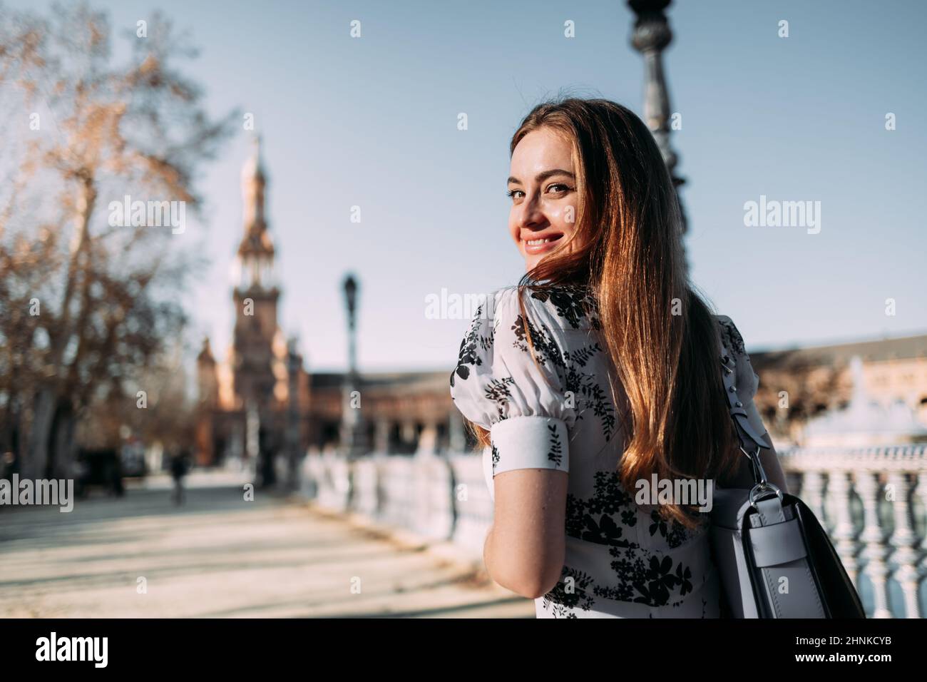 Belle jeune femme souriante qui se tourne vers l'appareil photo tout en faisant du tourisme à Séville, en Espagne Banque D'Images