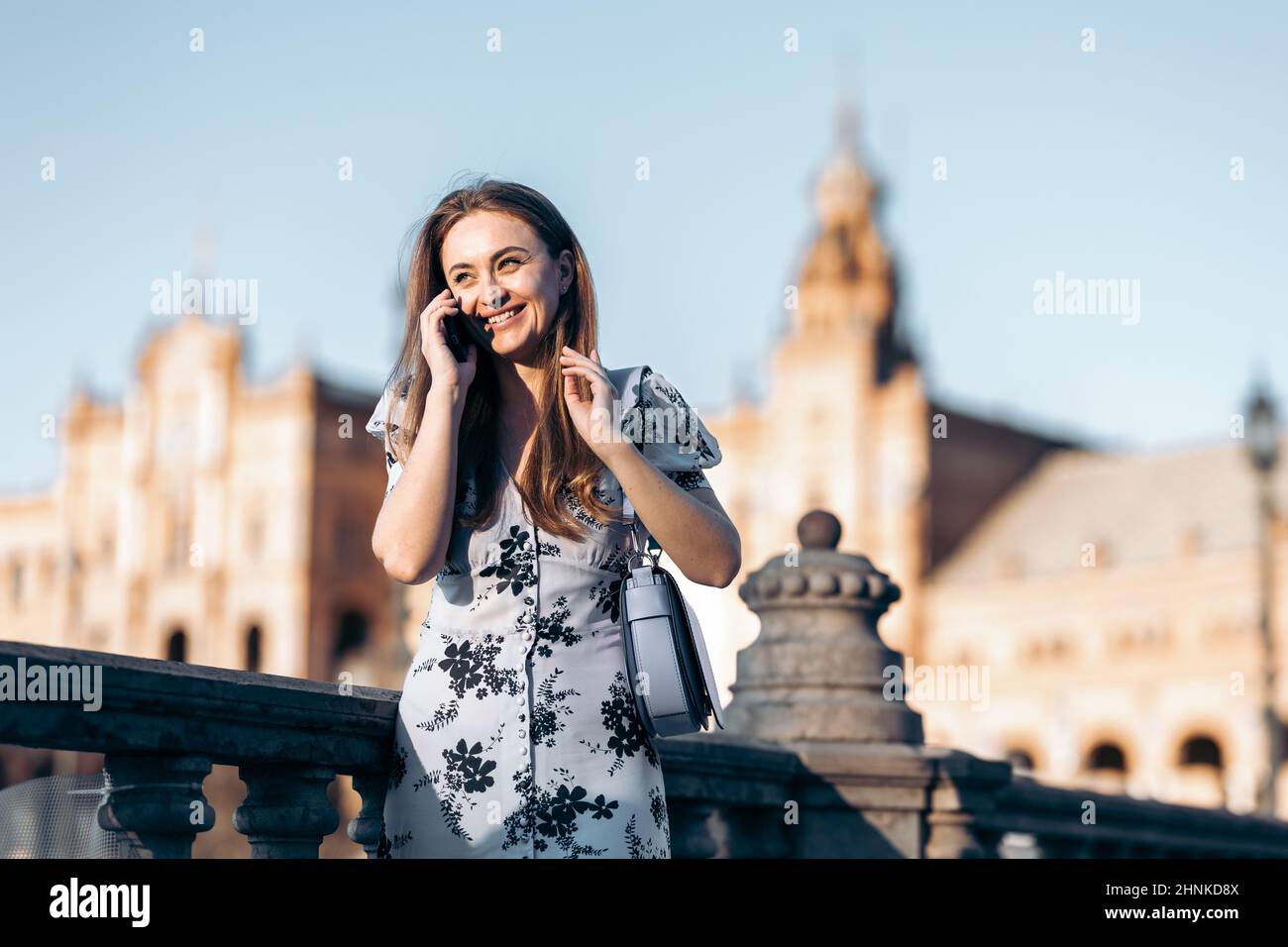 Portrait d'une jeune femme souriante et attrayante parlant sur son smartphone depuis une ville d'Europe Banque D'Images