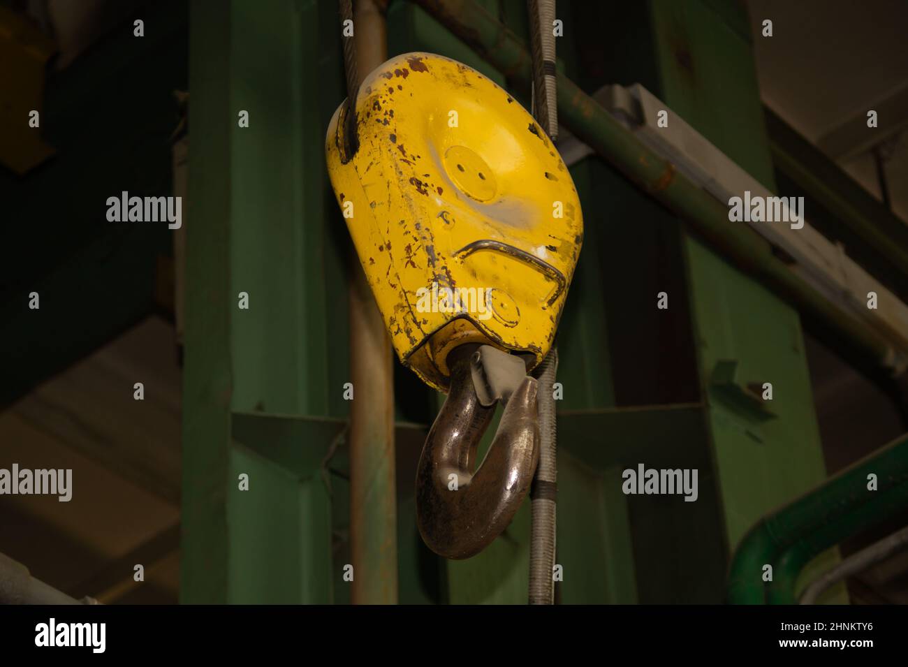 Crochet de grue jaune industriel suspendu en usine Banque D'Images