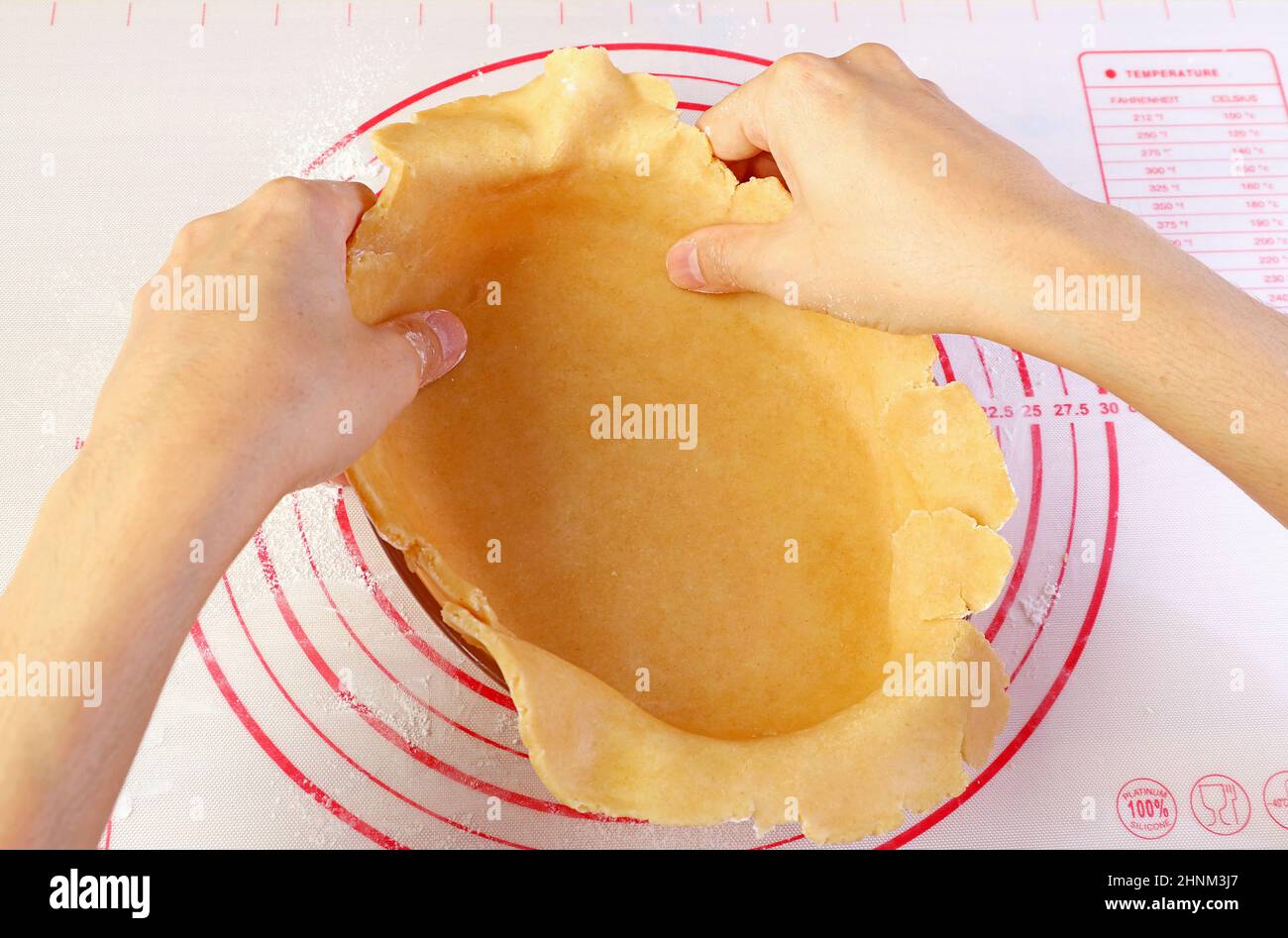 La main de l'homme façonne la pâte dans le bol de cuisson pour cuire la croûte de tarte Banque D'Images
