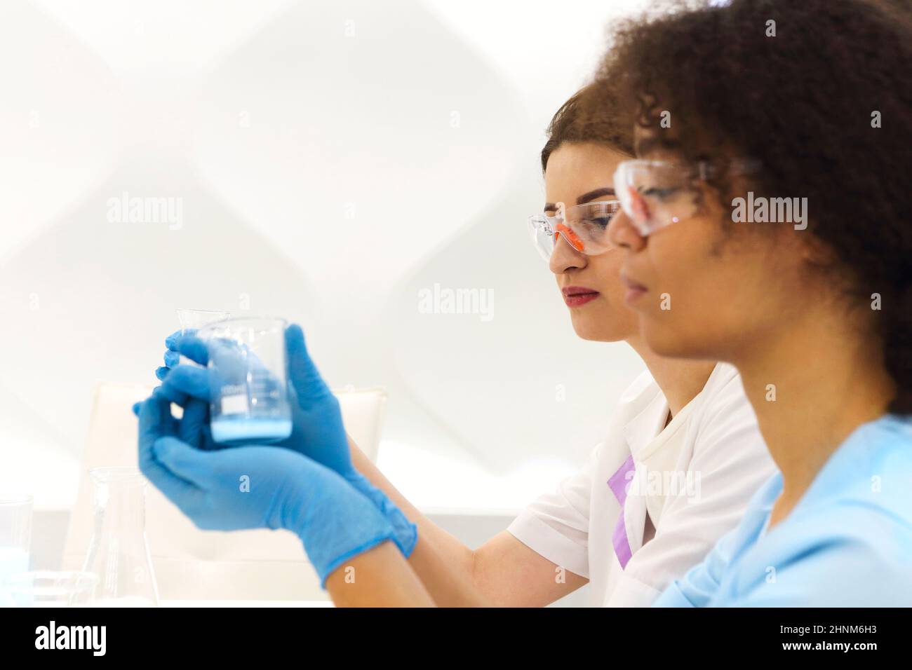 Laboratoire de test COVID-19. Deux femmes scientifiques de laboratoire médical collègues portant des lunettes travaillant avec des tubes à essai, multi-ethnique étudiants diplômés travail Banque D'Images