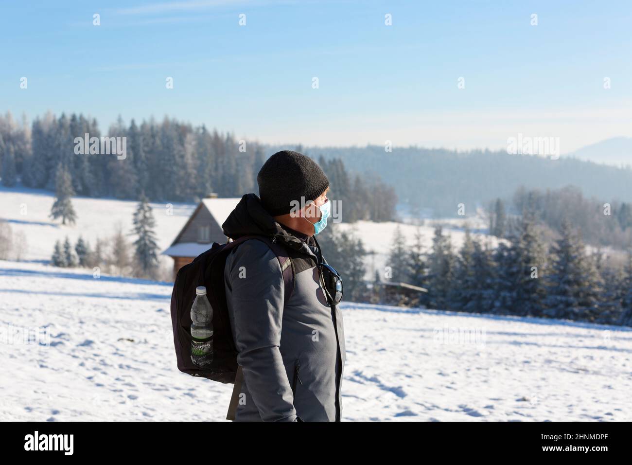 Homme âgé portant un masque de protection en raison de la pandémie de coronovirus Covid-19, marchant dans les montagnes en hiver, parc national de Gorce, Pologne. Banque D'Images