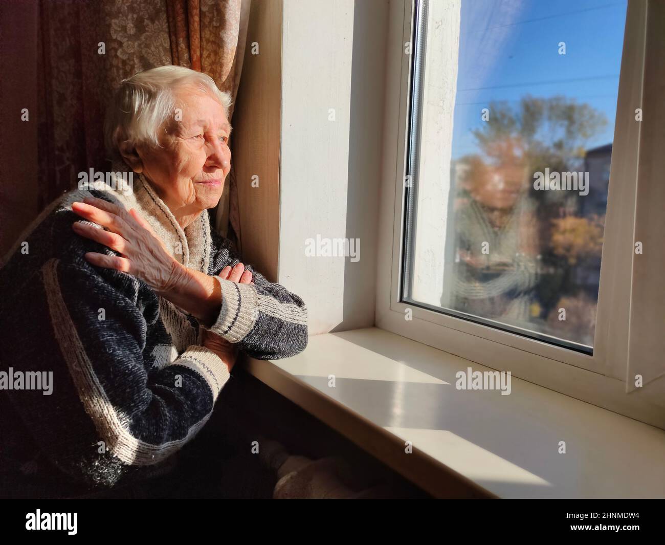 Vieille Femme solitaire assis près de la fenêtre de sa chambre. Banque D'Images