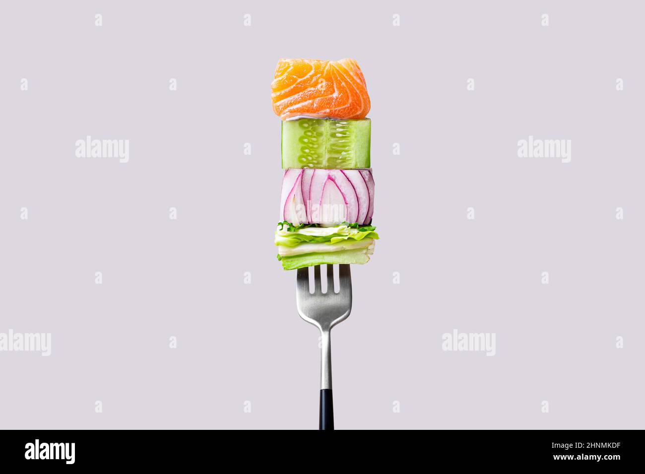 Fourchette avec nourriture sur elle: Délicieux filet de saumon, concombre, oignon, salade verte Banque D'Images
