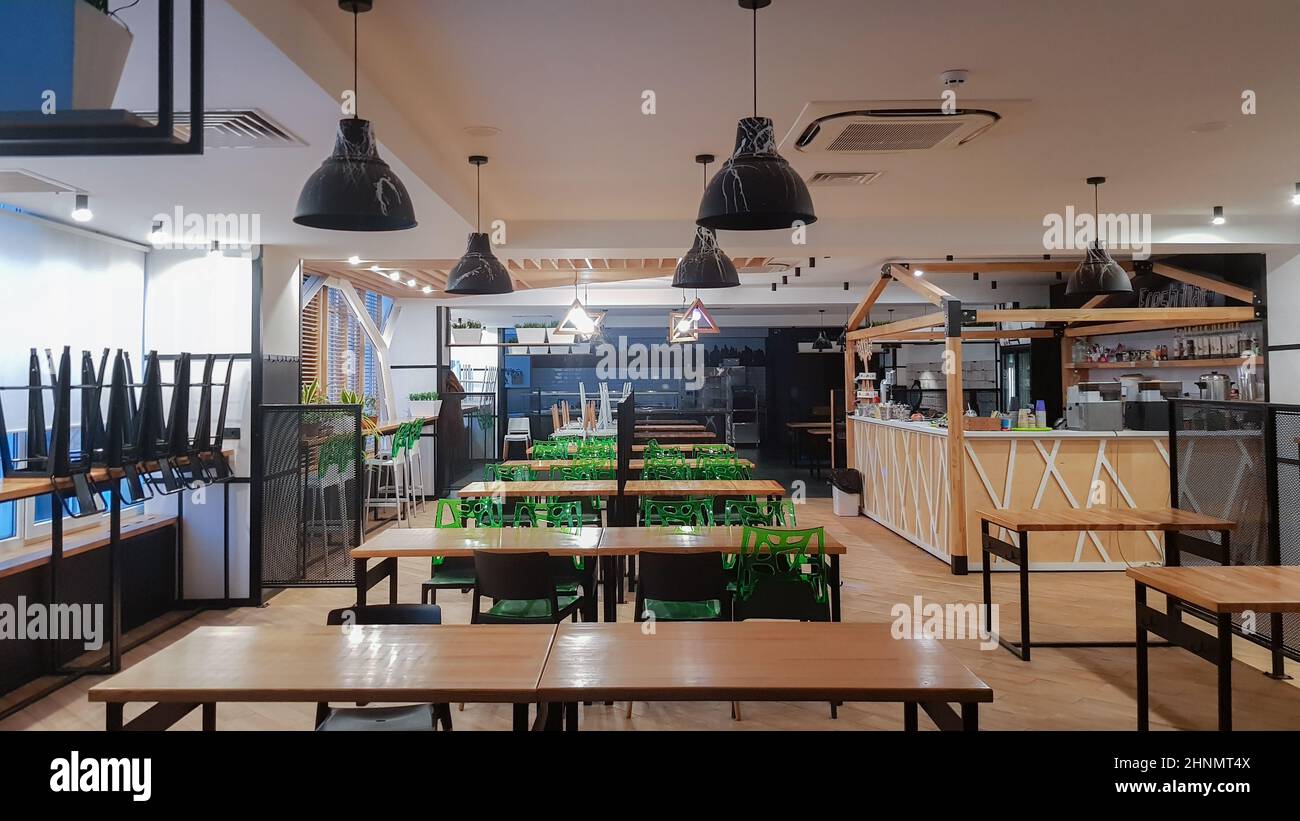 Cafétéria, pas de personnes salle à manger avec des tables en bois et des chaises vertes. Intérieur avec éléments en bois et en métal. Salle à manger moderne avec éclairage par fenêtre. Ukraine, Kiev - 19 février 2021 Banque D'Images